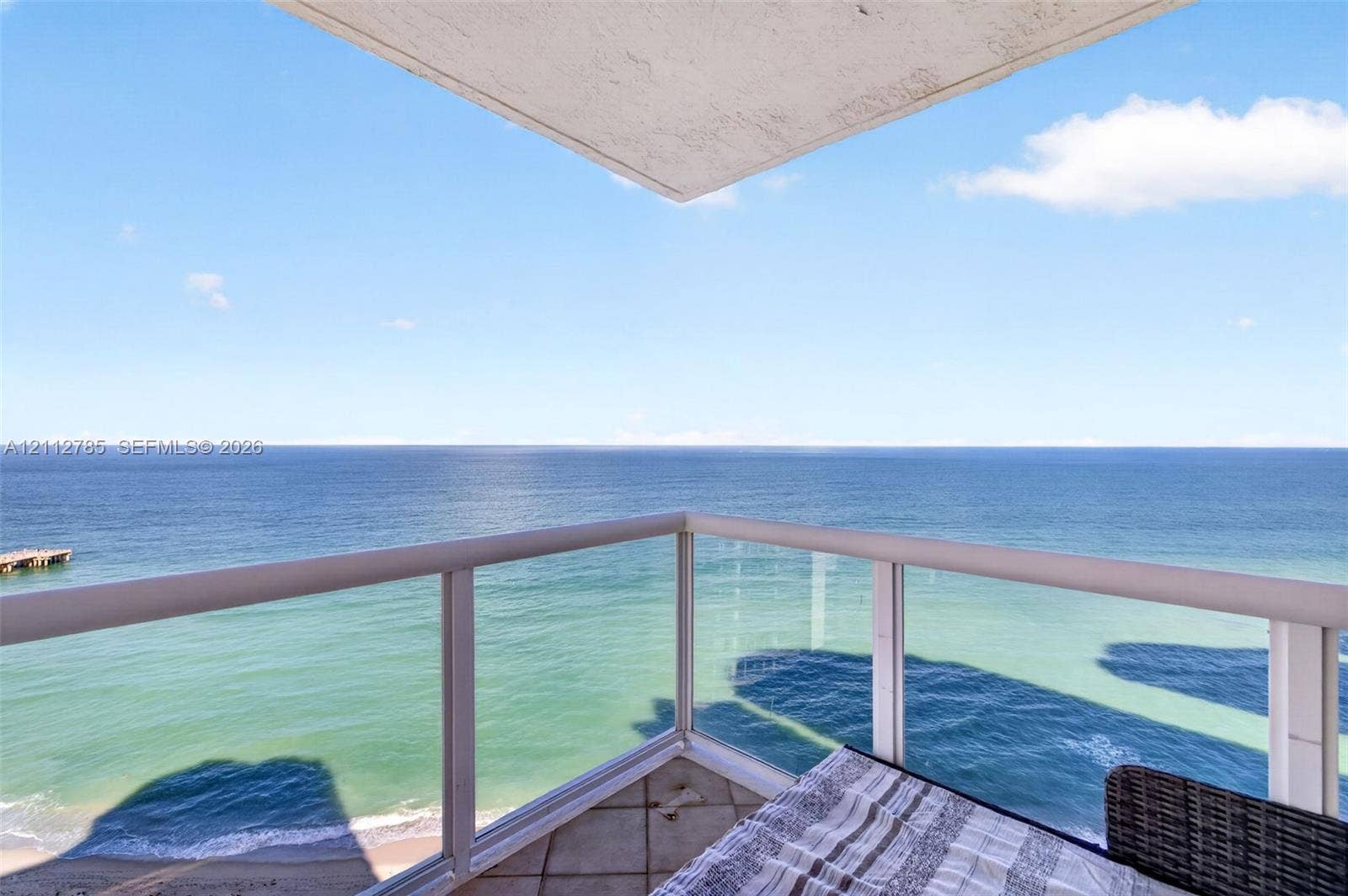 16425 Collins Avenue, #2016, Sunny Isles Beach, FL 33160 Covered balcony with glass panel railing and tile flooring, featuring an expansive ocean panorama