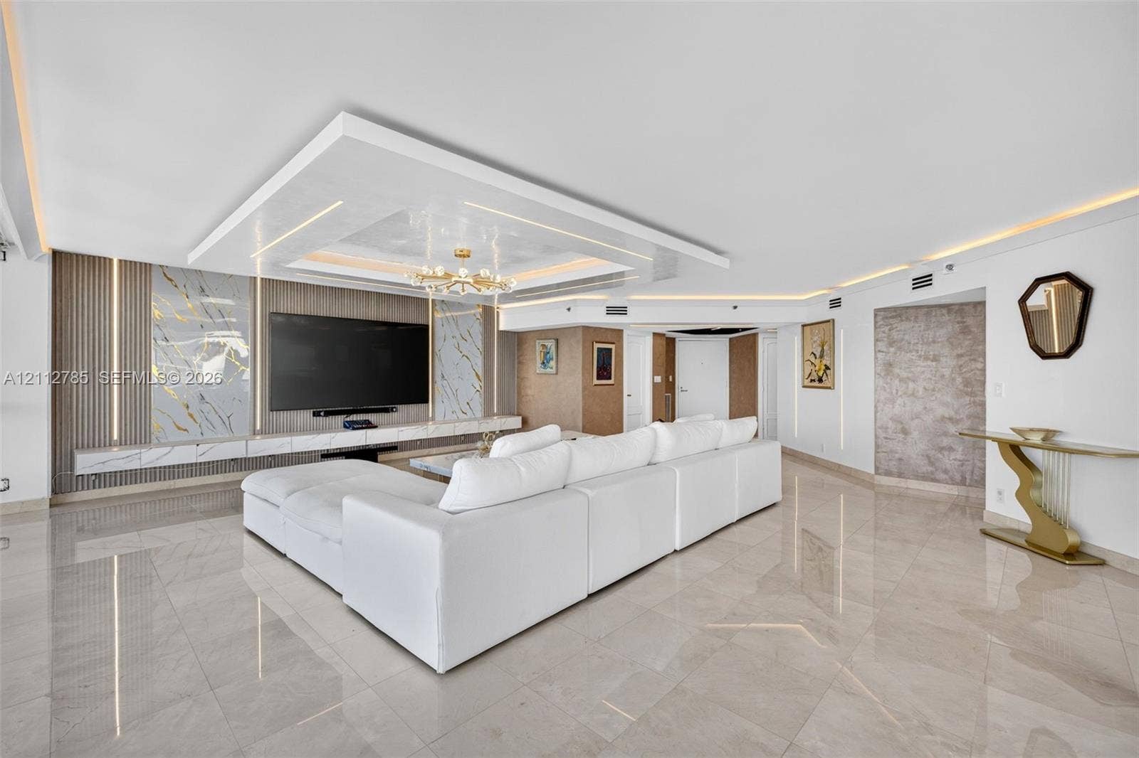 16425 Collins Avenue, #2016, Sunny Isles Beach, FL 33160 Polished stone flooring, custom tray ceiling with integrated recessed lighting, and wall-to-wall stone slab media center with vertical LED accent panels