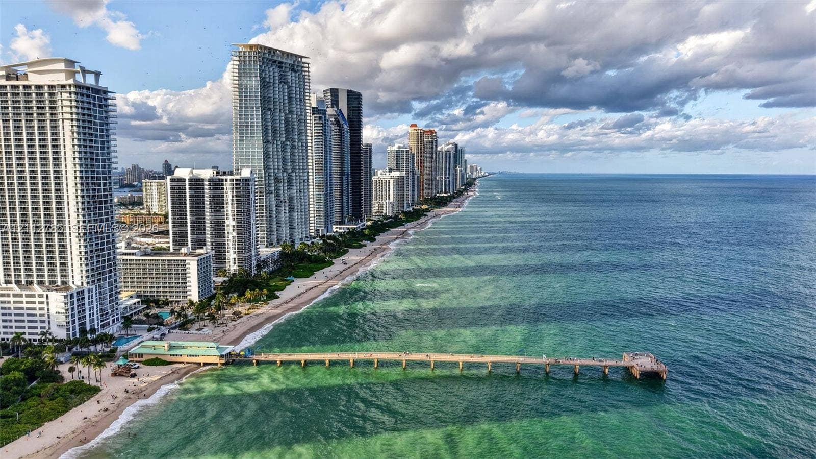 16425 Collins Avenue, #2016, Sunny Isles Beach, FL 33160 Coastal high-rise buildings situated along a sandy shoreline with direct ocean access and a prominent structural pier