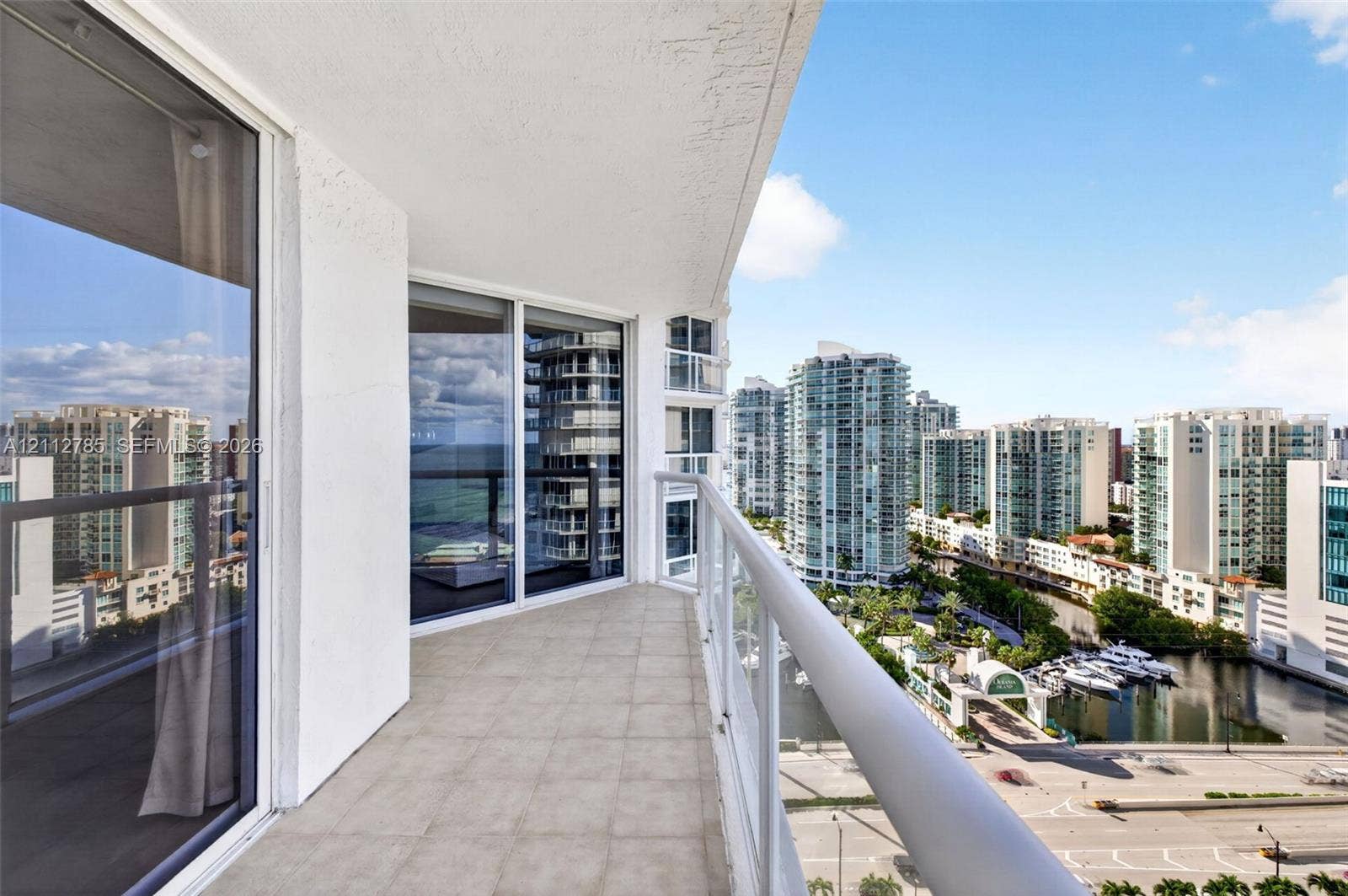 16425 Collins Avenue, #2016, Sunny Isles Beach, FL 33160 Covered balcony featuring tile flooring, glass panel railings, and floor-to-ceiling sliding glass doors