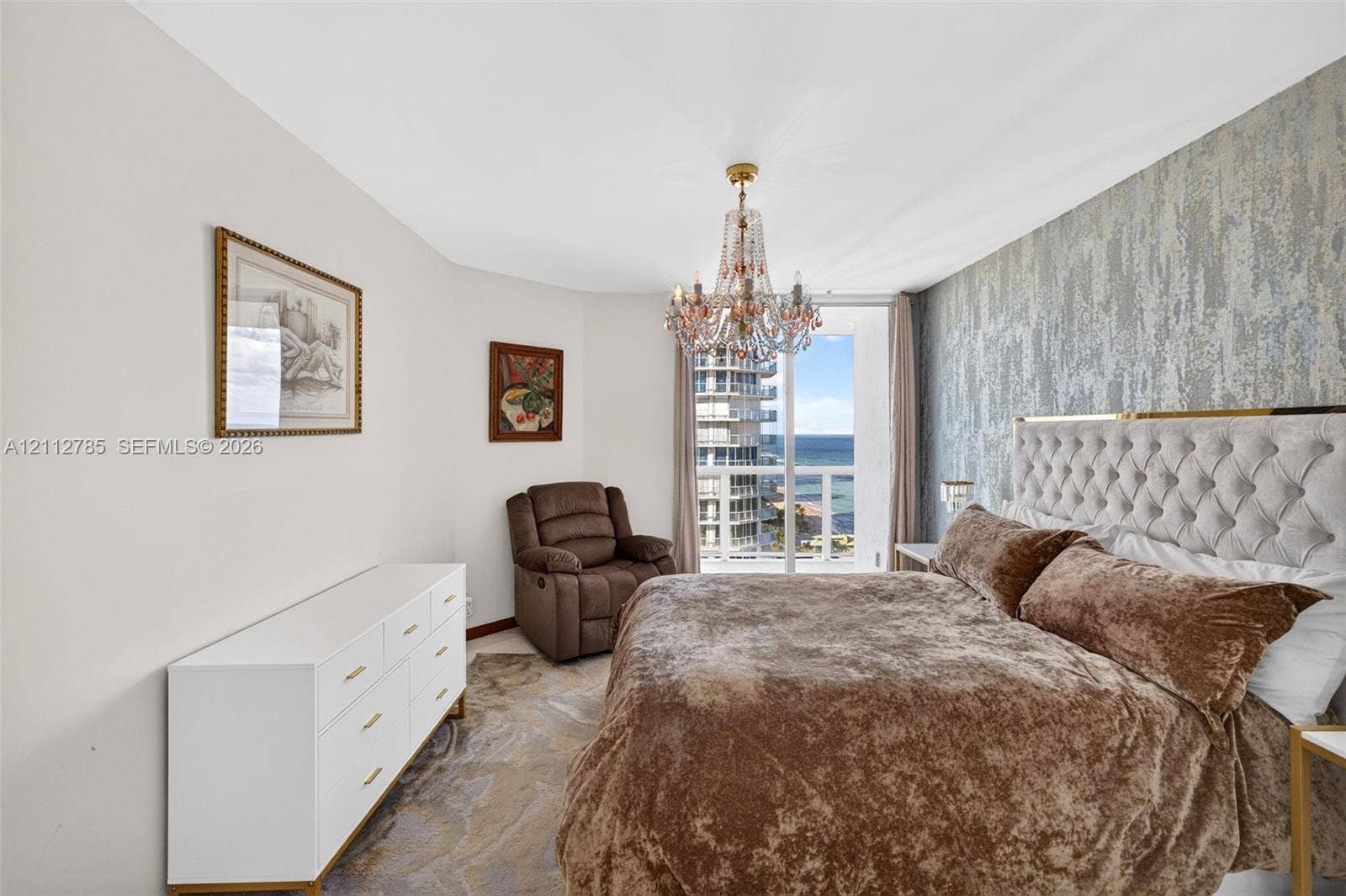 16425 Collins Avenue, #2016, Sunny Isles Beach, FL 33160 Textured accent wall, crystal chandelier, and floor-to-ceiling glass door opening to a private balcony