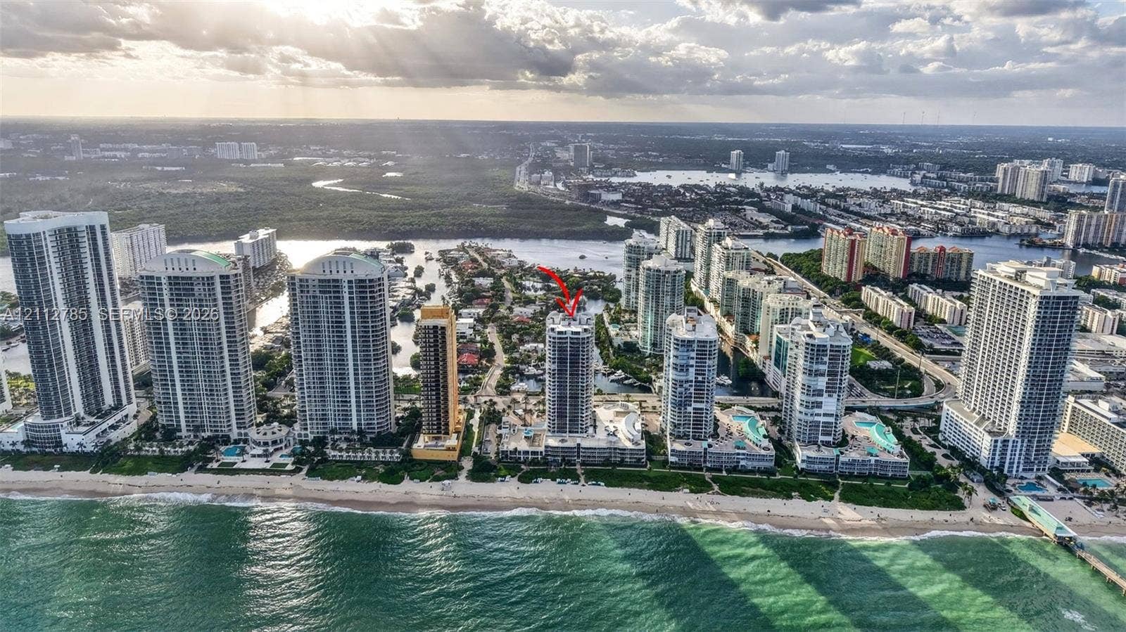 16425 Collins Avenue, #2016, Sunny Isles Beach, FL 33160 Aerial perspective of a high-rise tower positioned along a coastal shoreline, featuring direct ocean access, integrated building amenities, proximity to local waterways, and surrounding urban infrastructure