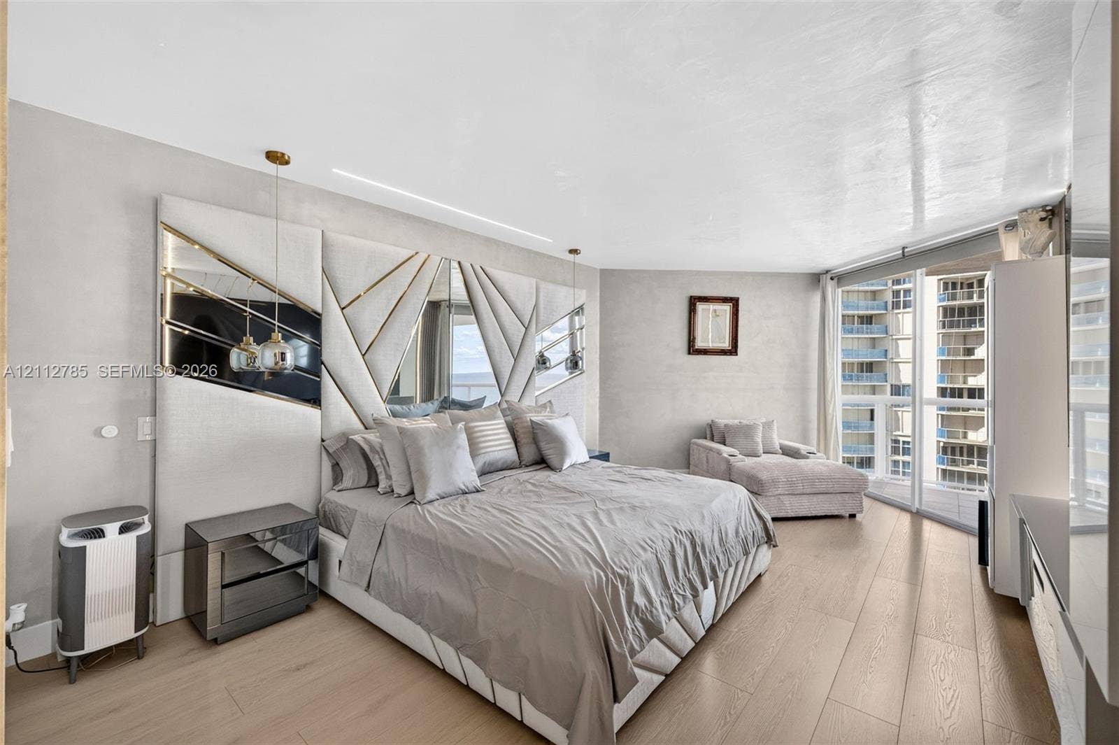 16425 Collins Avenue, #2016, Sunny Isles Beach, FL 33160 Custom floor-to-ceiling geometric headboard with integrated mirror panels, wood-finish flooring, recessed ceiling lighting, and floor-to-ceiling windows