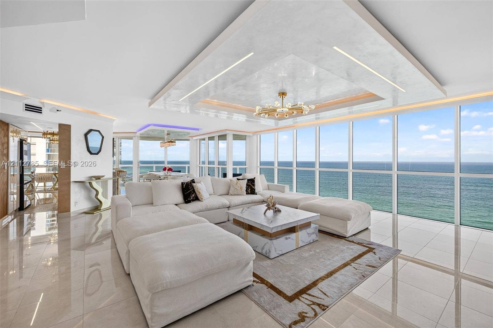 16425 Collins Avenue, #2016, Sunny Isles Beach, FL 33160 Floor-to-ceiling glass windows, recessed tray ceiling with accent lighting, polished tile flooring, and custom chandelier
