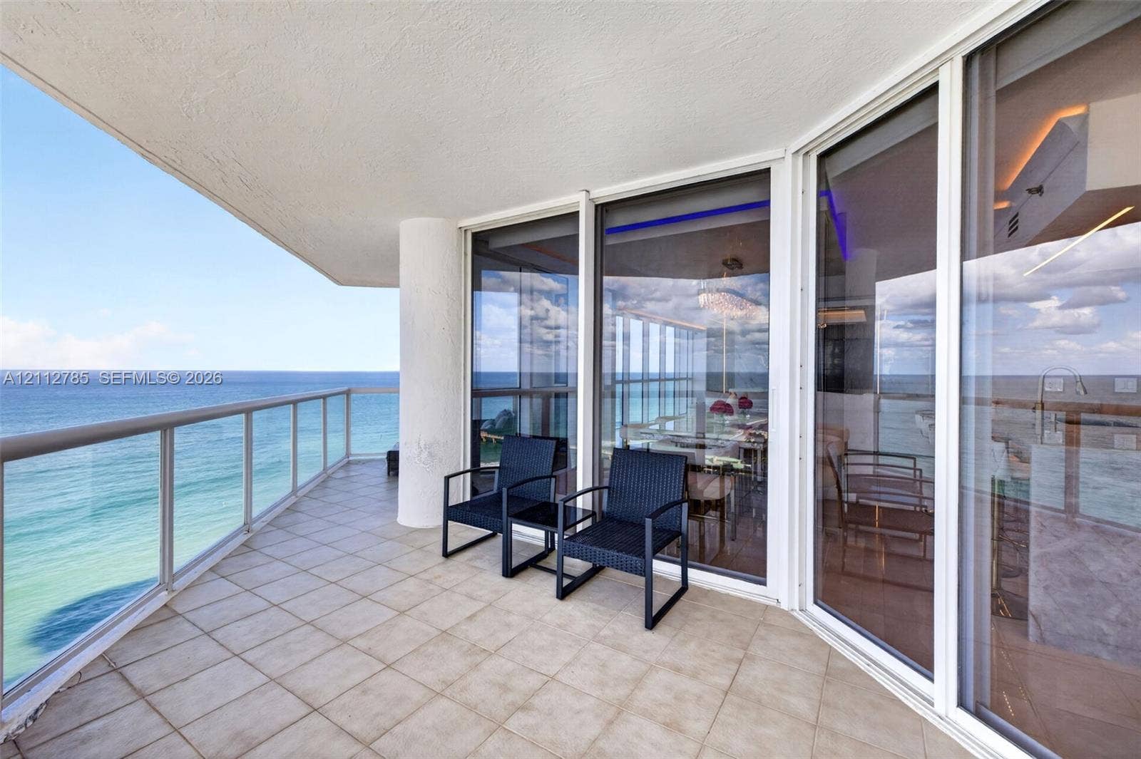 16425 Collins Avenue, #2016, Sunny Isles Beach, FL 33160 Covered balcony featuring tile flooring, glass panel railing, and expansive floor-to-ceiling sliding glass doors