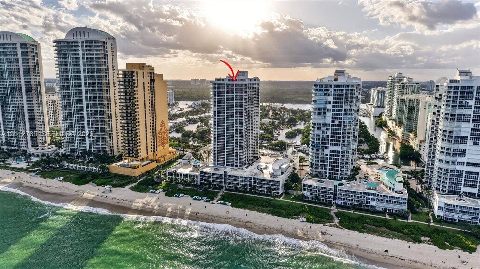 16425 Collins Avenue, #2016, Sunny Isles Beach, FL 33160 High-rise residential building featuring floor-to-ceiling glass windows, multiple balconies, and a prime coastal location directly bordering the Atlantic Ocean