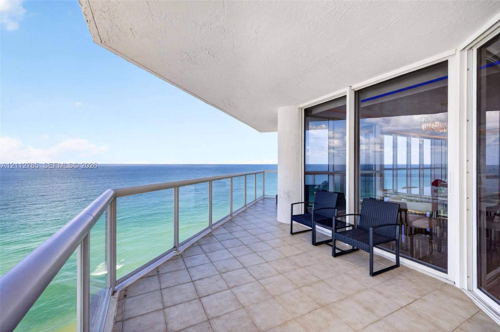 16425 Collins Avenue, #2016, Sunny Isles Beach, FL 33160 Covered balcony featuring tile flooring, aluminum railing, and floor-to-ceiling glass paneling overlooking the ocean