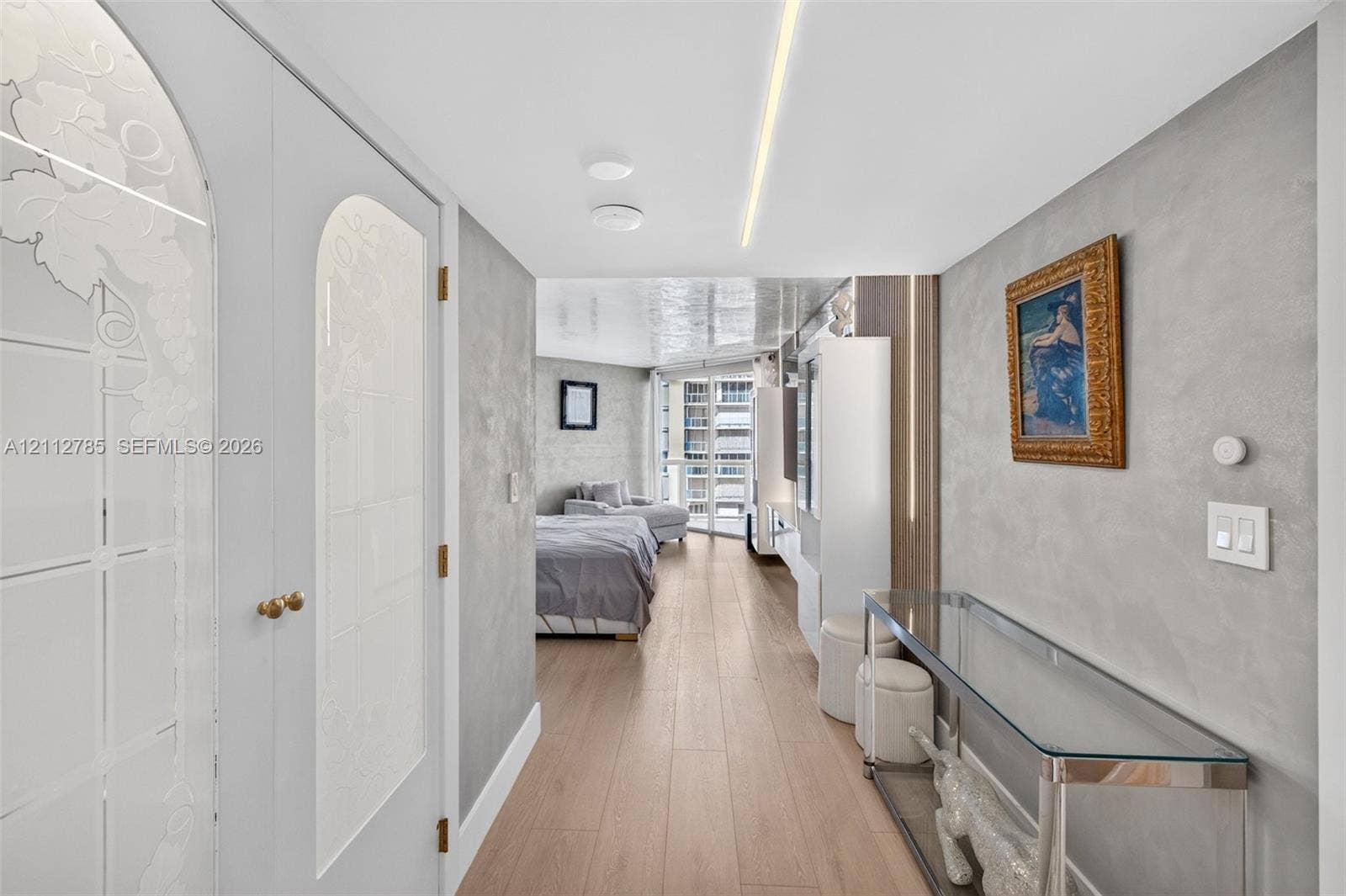 16425 Collins Avenue, #2016, Sunny Isles Beach, FL 33160 Interior space featuring wood-finish flooring, textured metallic wall finishes, recessed linear ceiling lighting, and custom double doors with arched glass panels