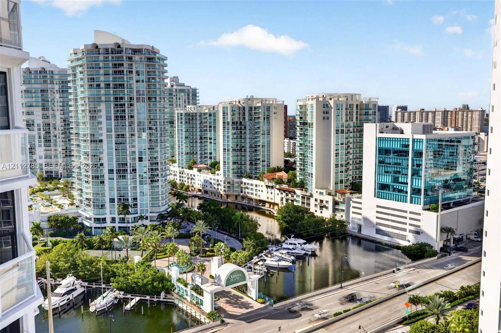 16425 Collins Avenue, #2016, Sunny Isles Beach, FL 33160 High-rise perspective featuring expansive glass-facade towers, deep-water marina with boat slips, paved multi-level parking structures, and lush tropical landscaping