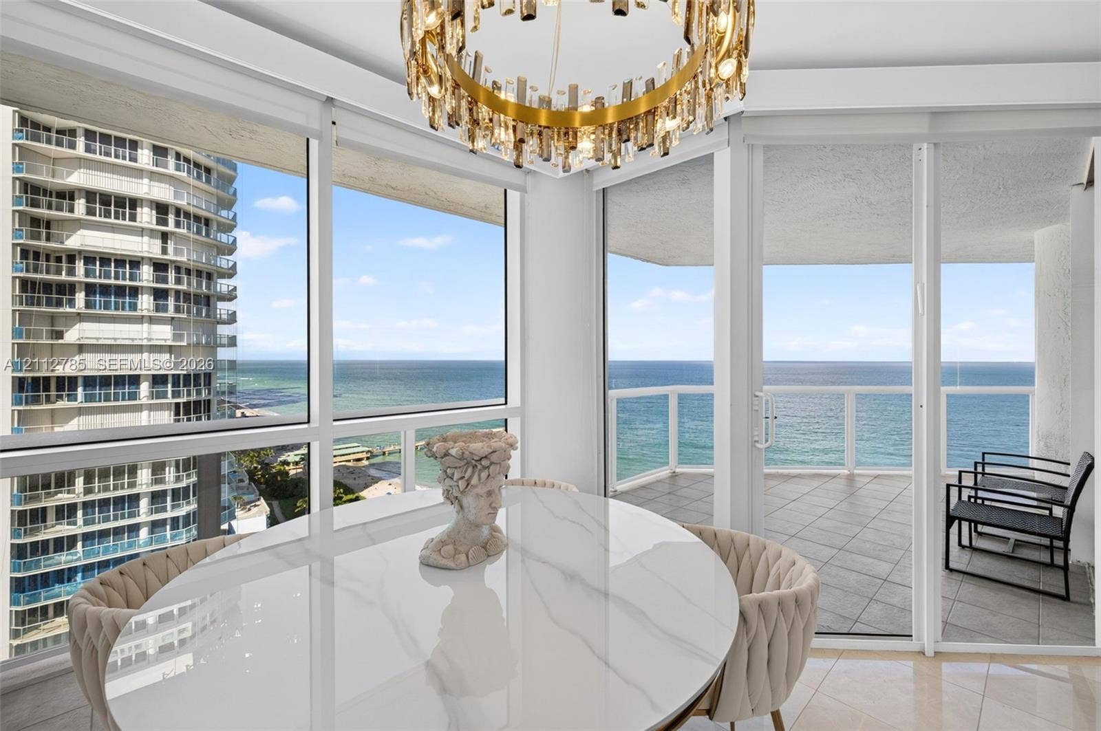 16425 Collins Avenue, #2016, Sunny Isles Beach, FL 33160 Floor-to-ceiling windows, circular multi-tiered crystal chandelier, wrap-around balcony with tiled flooring, and expansive ocean and coastal vistas