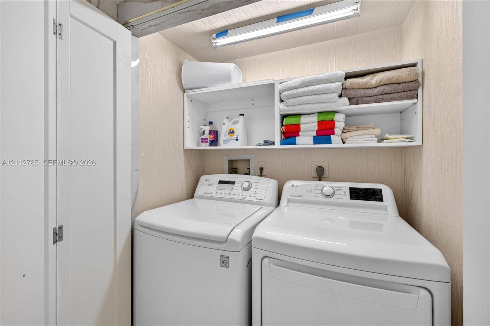 16425 Collins Avenue, #2016, Sunny Isles Beach, FL 33160 Laundry area featuring built-in white shelving, overhead task lighting, and bi-fold closet doors