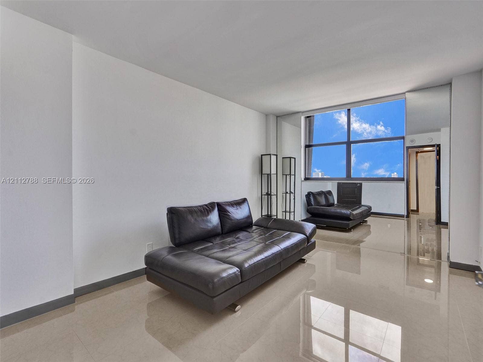 Large-format tile flooring, expansive floor-to-ceiling windows, and mirrored wall accents