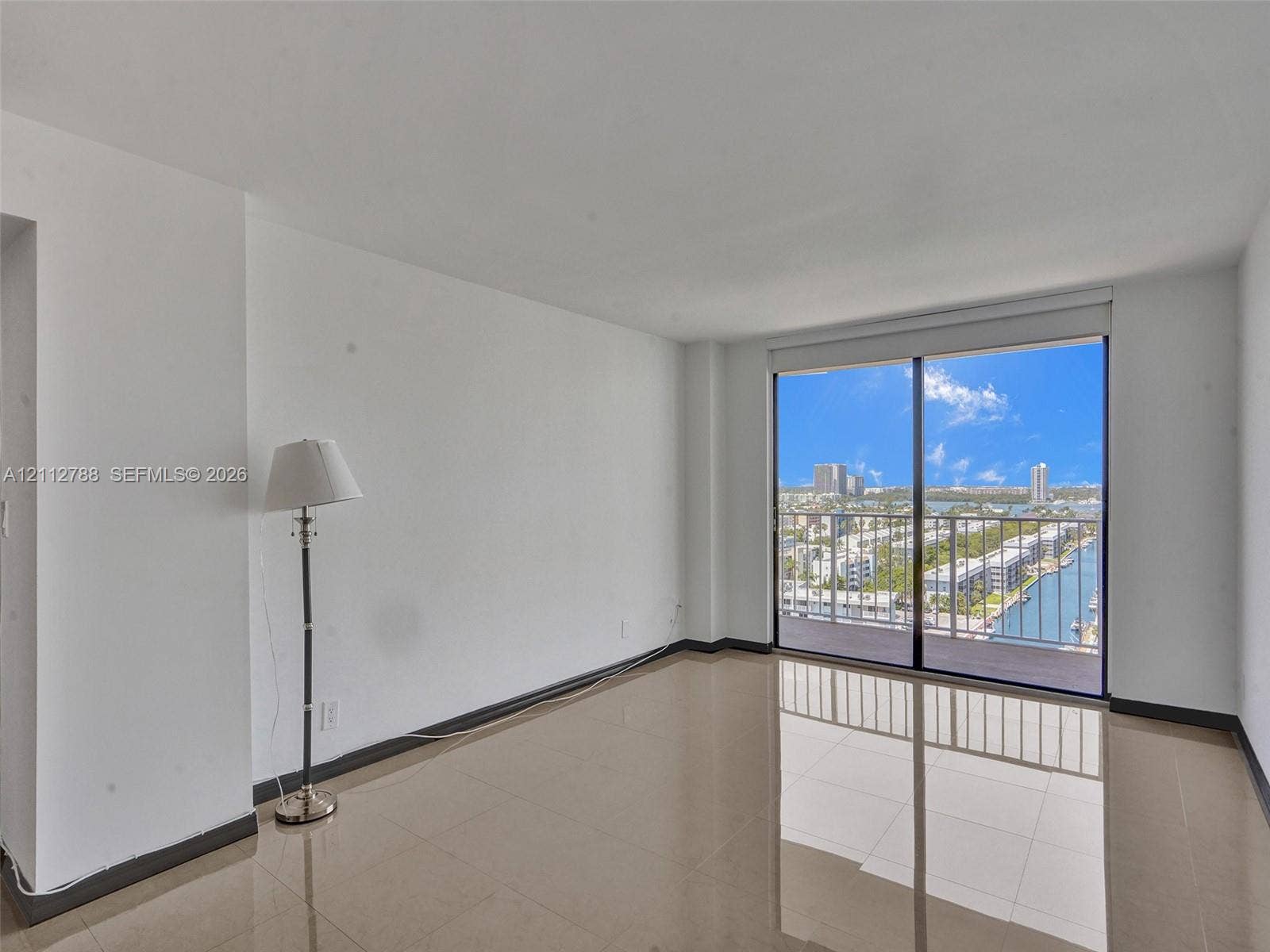 Interior space featuring large-format tile flooring, floor-to-ceiling glass sliding doors, and a private balcony with metal railing