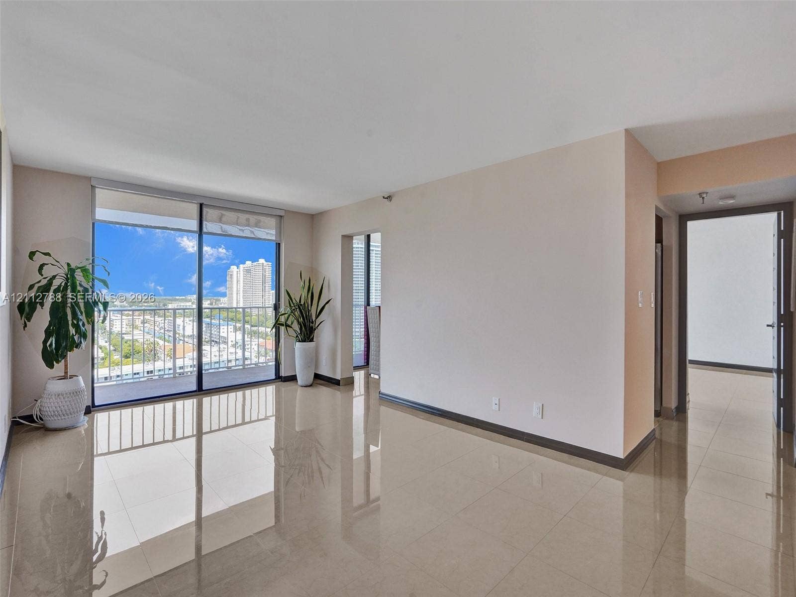 Open-concept interior featuring large-format tile flooring, expansive sliding glass doors, and a private balcony