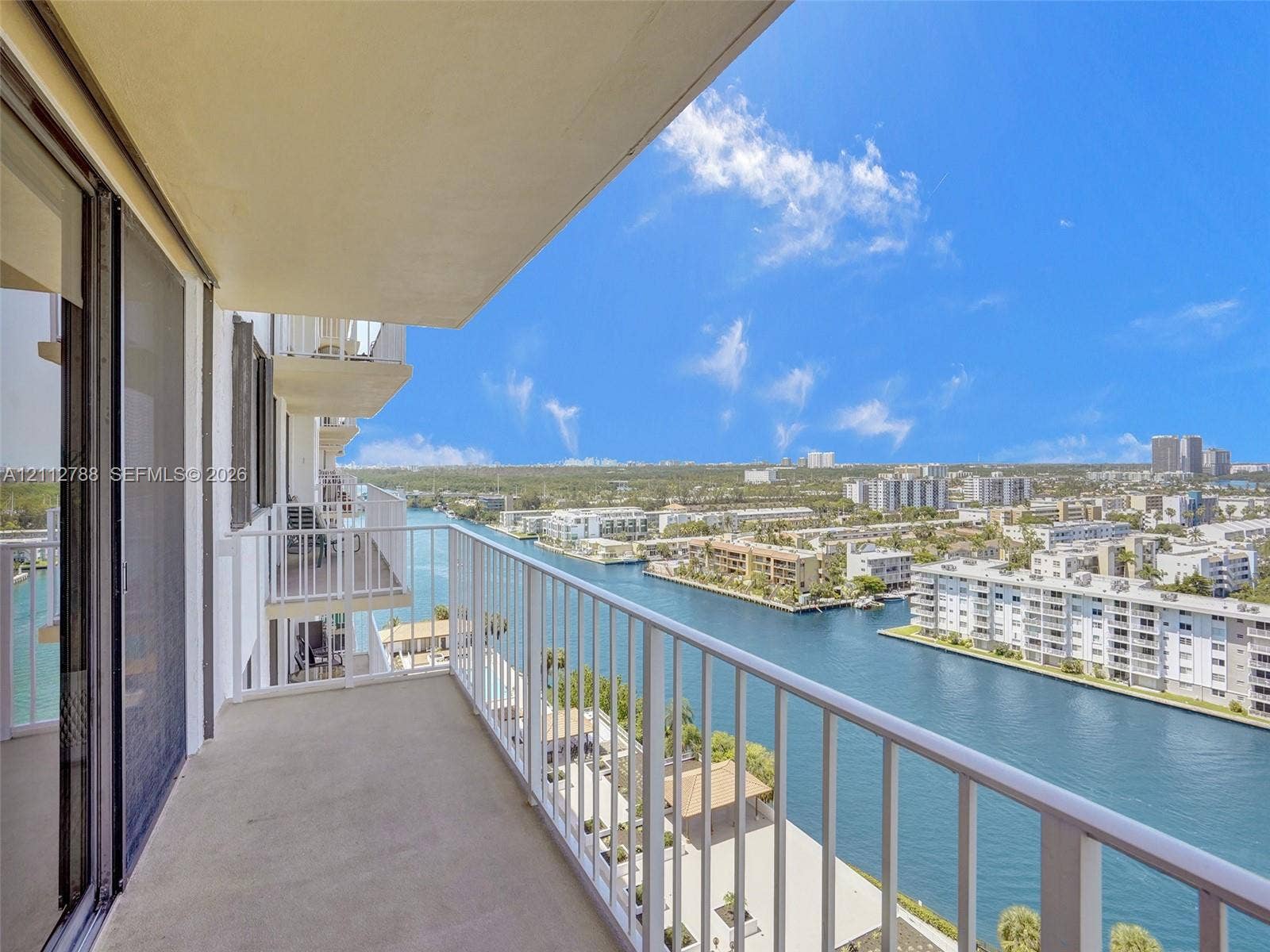 Covered balcony featuring concrete flooring and white metal railings