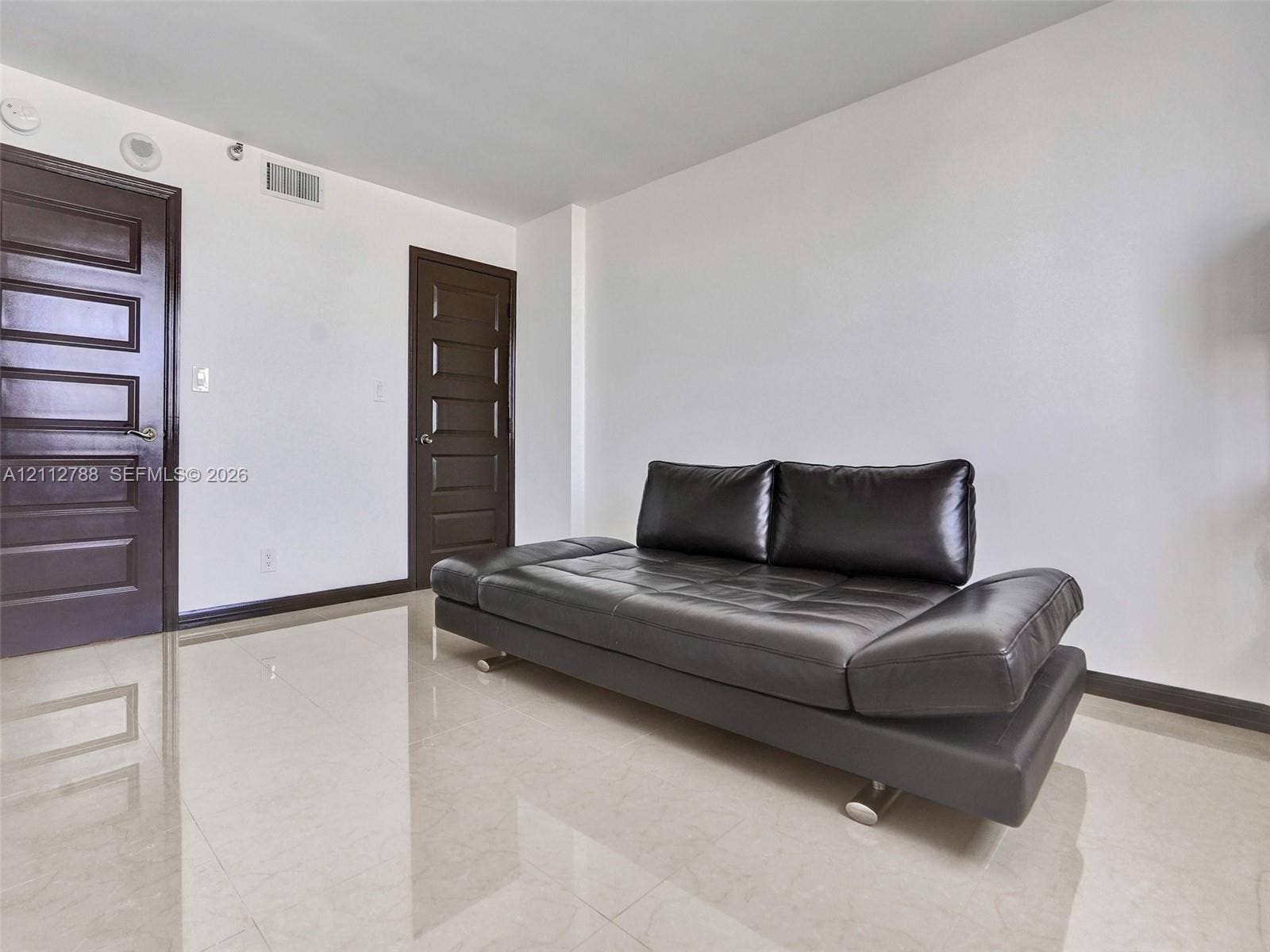 Neutral-toned tile flooring, two solid-core five-panel interior doors with dark finish, and high-gloss walls
