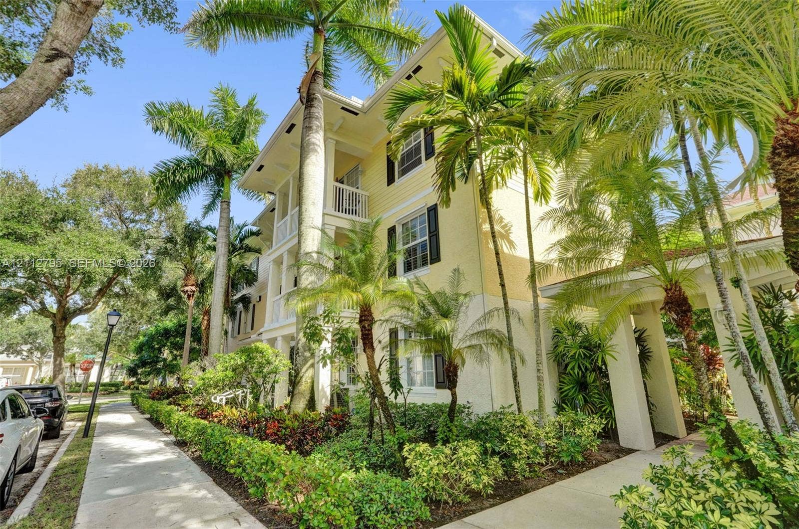 275 Murcia Drive, #205, Jupiter, FL 33458 Multi-story exterior featuring lap siding, shutter-framed windows, multi-level balconies with railing, and integrated palm tree landscaping