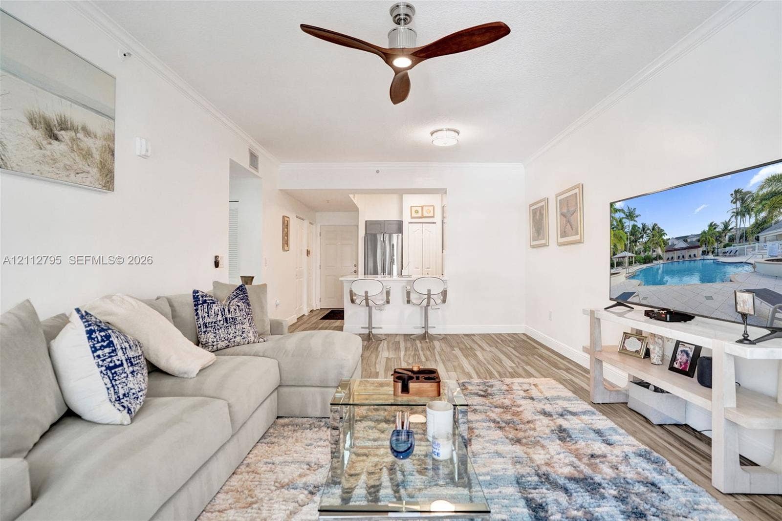 275 Murcia Drive, #205, Jupiter, FL 33458 Open-concept room featuring wood-finish flooring, a contemporary three-blade ceiling fan, and crown molding