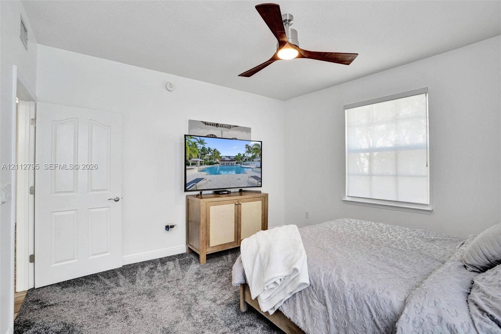 275 Murcia Drive, #205, Jupiter, FL 33458 Neutral interior featuring wall-to-wall carpeting, a three-blade ceiling fan with integrated lighting, and a multi-pane window with a roller shade