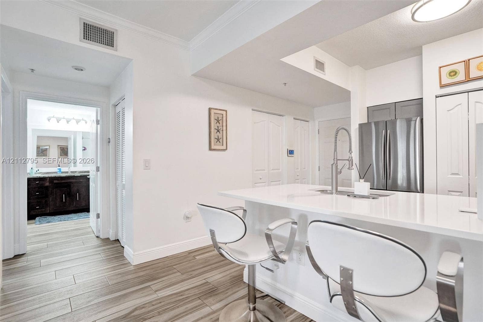275 Murcia Drive, #205, Jupiter, FL 33458 Kitchen featuring a breakfast bar with a solid surface countertop, stainless steel refrigerator, pull-down chrome faucet, and wood-finish flooring