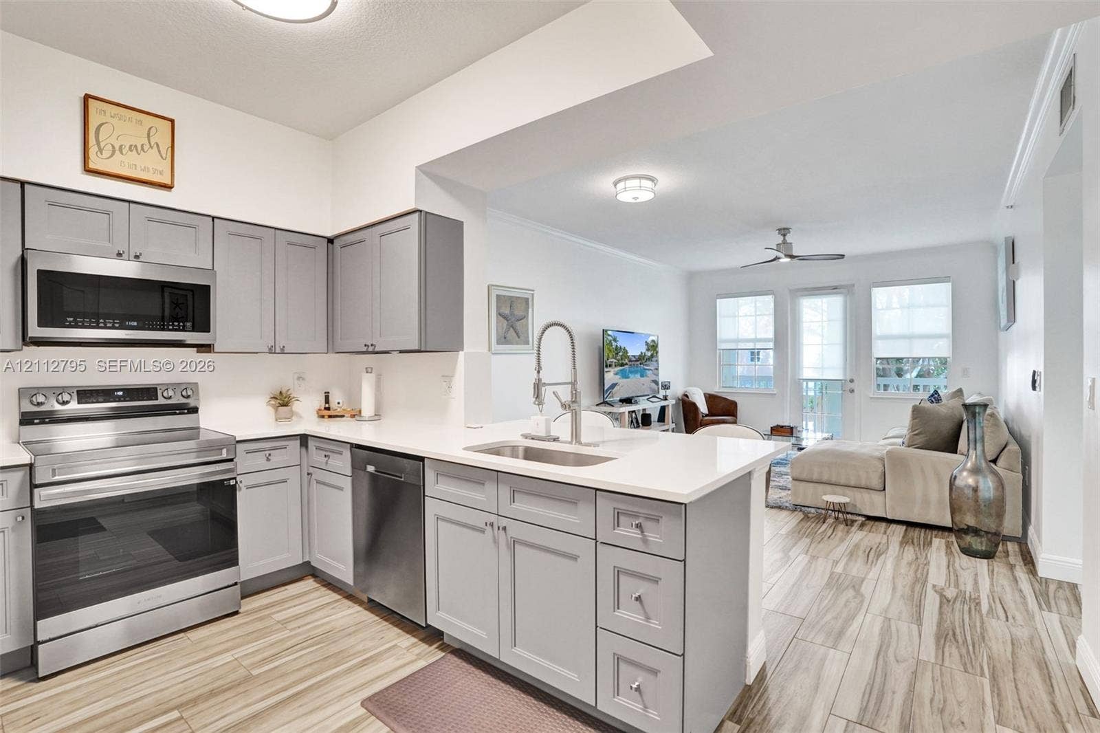 275 Murcia Drive, #205, Jupiter, FL 33458 Kitchen featuring grey shaker cabinetry, white countertops, stainless steel appliances, a stainless steel undermount sink with a pull-down faucet, and wood-finish flooring