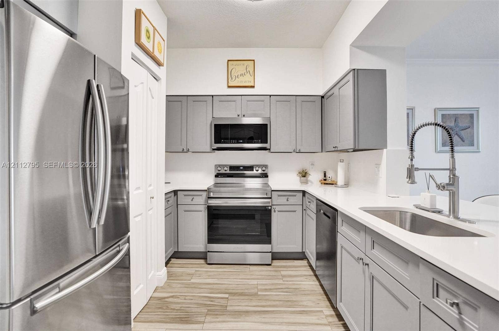 275 Murcia Drive, #205, Jupiter, FL 33458 Kitchen featuring grey shaker-style cabinetry, stainless steel appliances, solid surface countertops, wood-finish tile flooring, and a gooseneck faucet