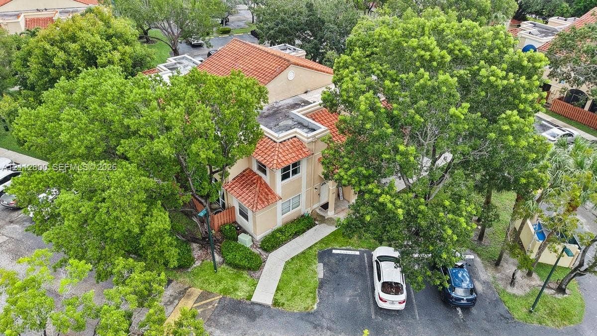 599 Racquet Club Road, #68-17, Weston, FL 33326 Aerial view of a multi-level structure featuring a terracotta tile roof, stucco exterior, paved walkway, and mature trees