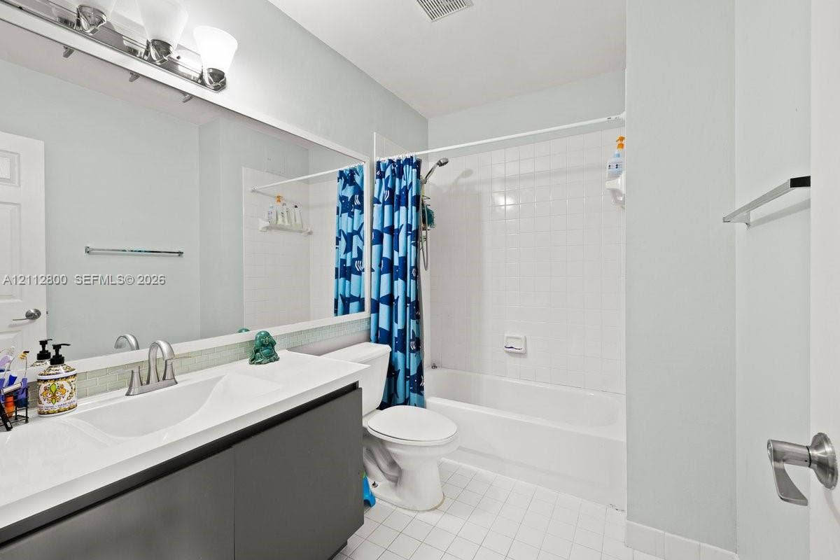 599 Racquet Club Road, #68-17, Weston, FL 33326 Full-width vanity with an integrated countertop, dark cabinetry, oversized wall mirror, three-light fixture, and a tub-shower combination with white tile surround