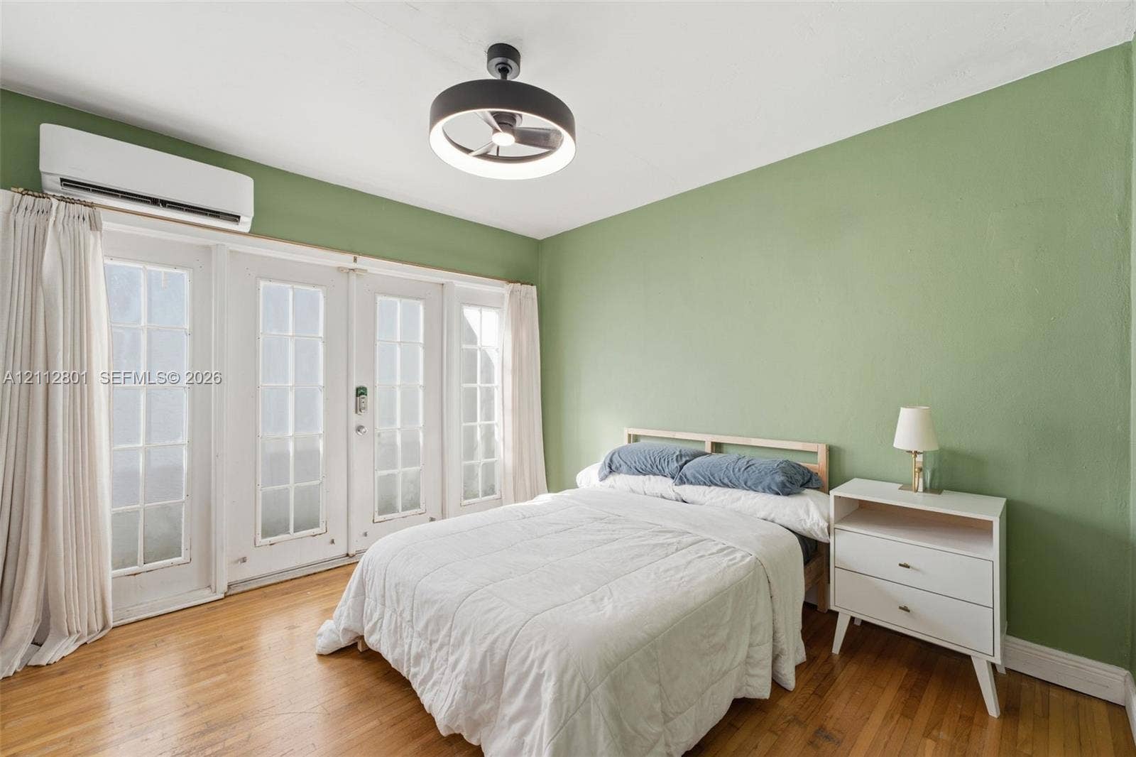 3241 SW 84th Court, Miami, FL 33155 Wood-finish flooring, wall-mounted ductless climate control unit, double French doors with glass panes, and a modern drum-style ceiling fan