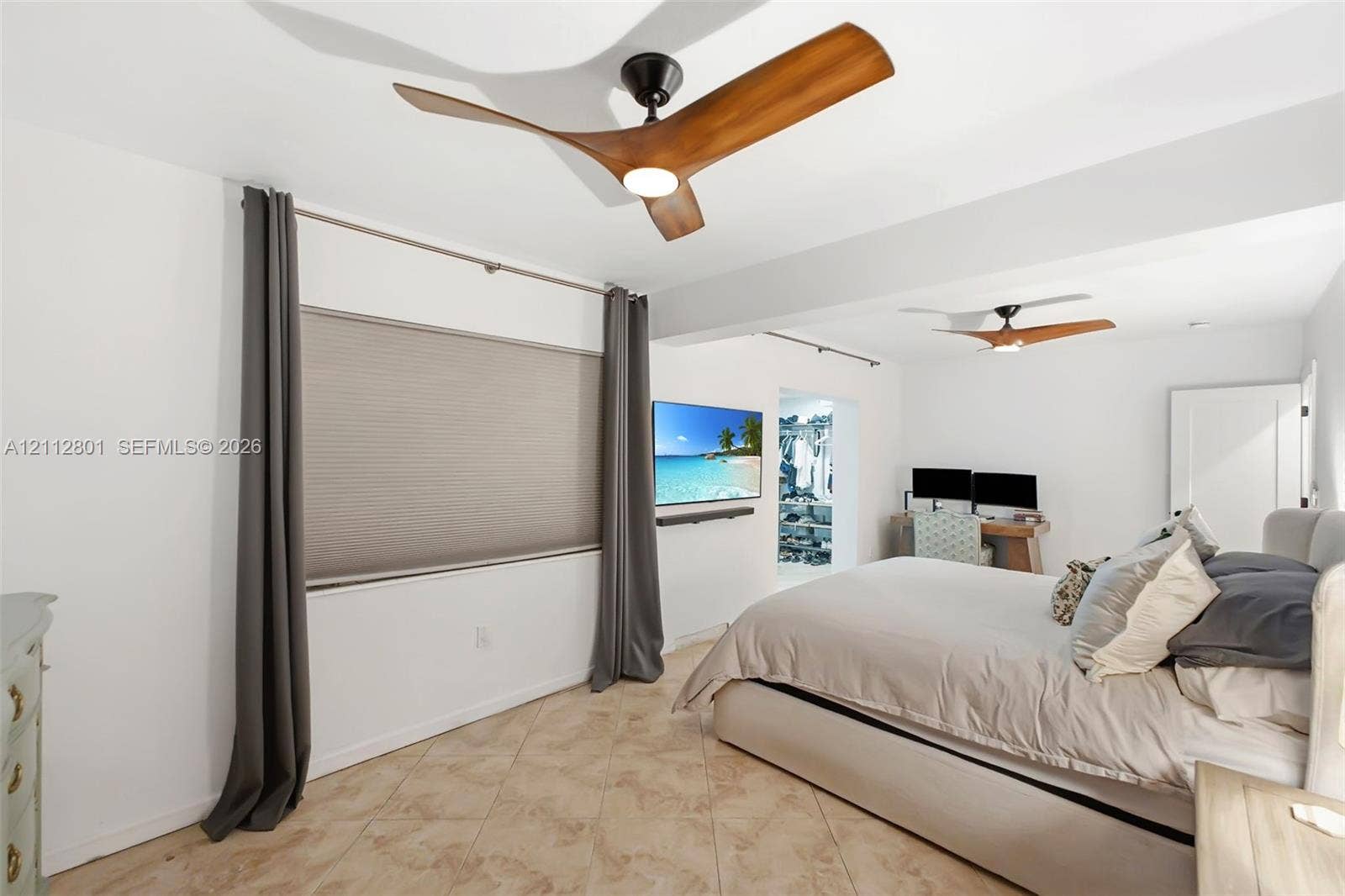 3241 SW 84th Court, Miami, FL 33155 High-ceilinged room featuring two modern three-blade ceiling fans with integrated light kits, neutral tile flooring, and neutral wall-mounted cellular shades