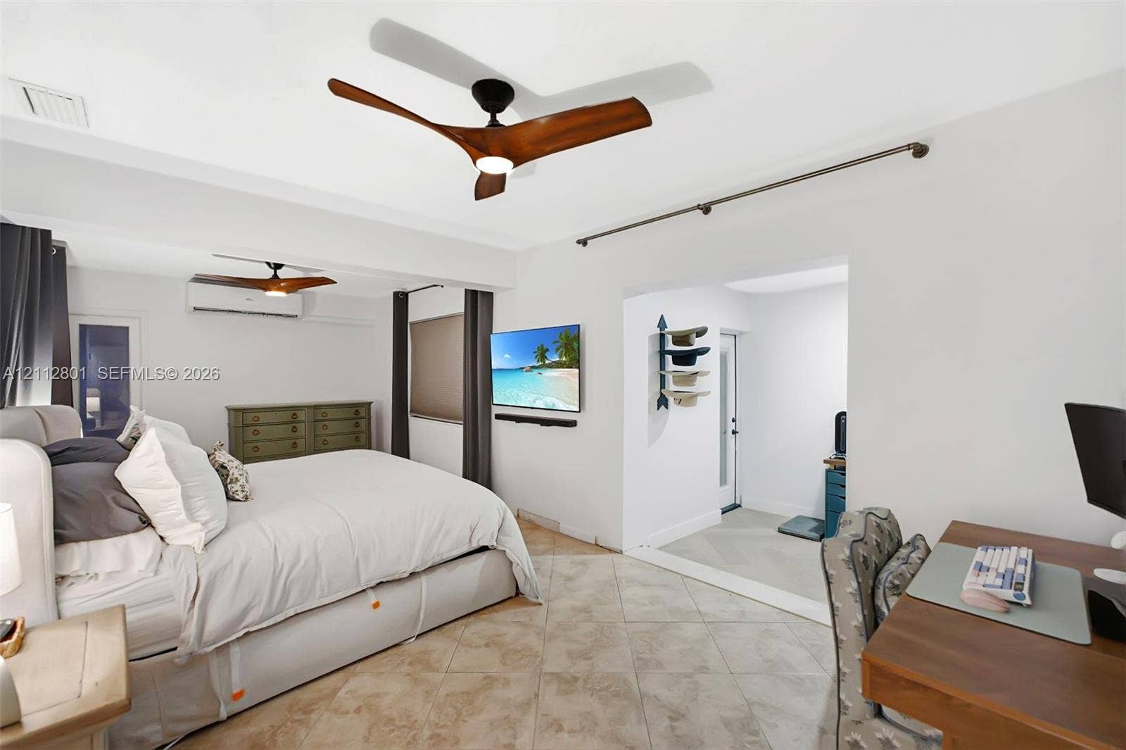 3241 SW 84th Court, Miami, FL 33155 Spacious room featuring neutral stone-finish tile flooring, dual modern three-blade ceiling fans, and a wall-mounted ductless climate control unit