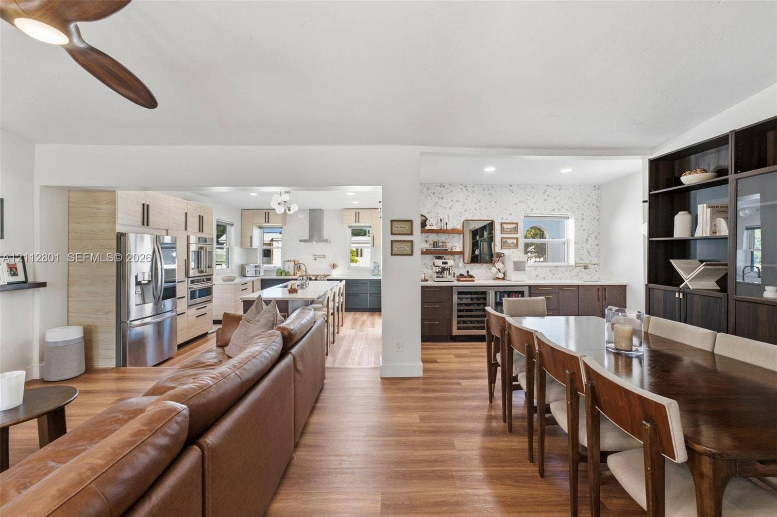 3241 SW 84th Court, Miami, FL 33155 Kitchen featuring stainless steel appliances, a center island with pendant lighting, wood-finish flooring, built-in dark wood shelving, and a wine refrigerator