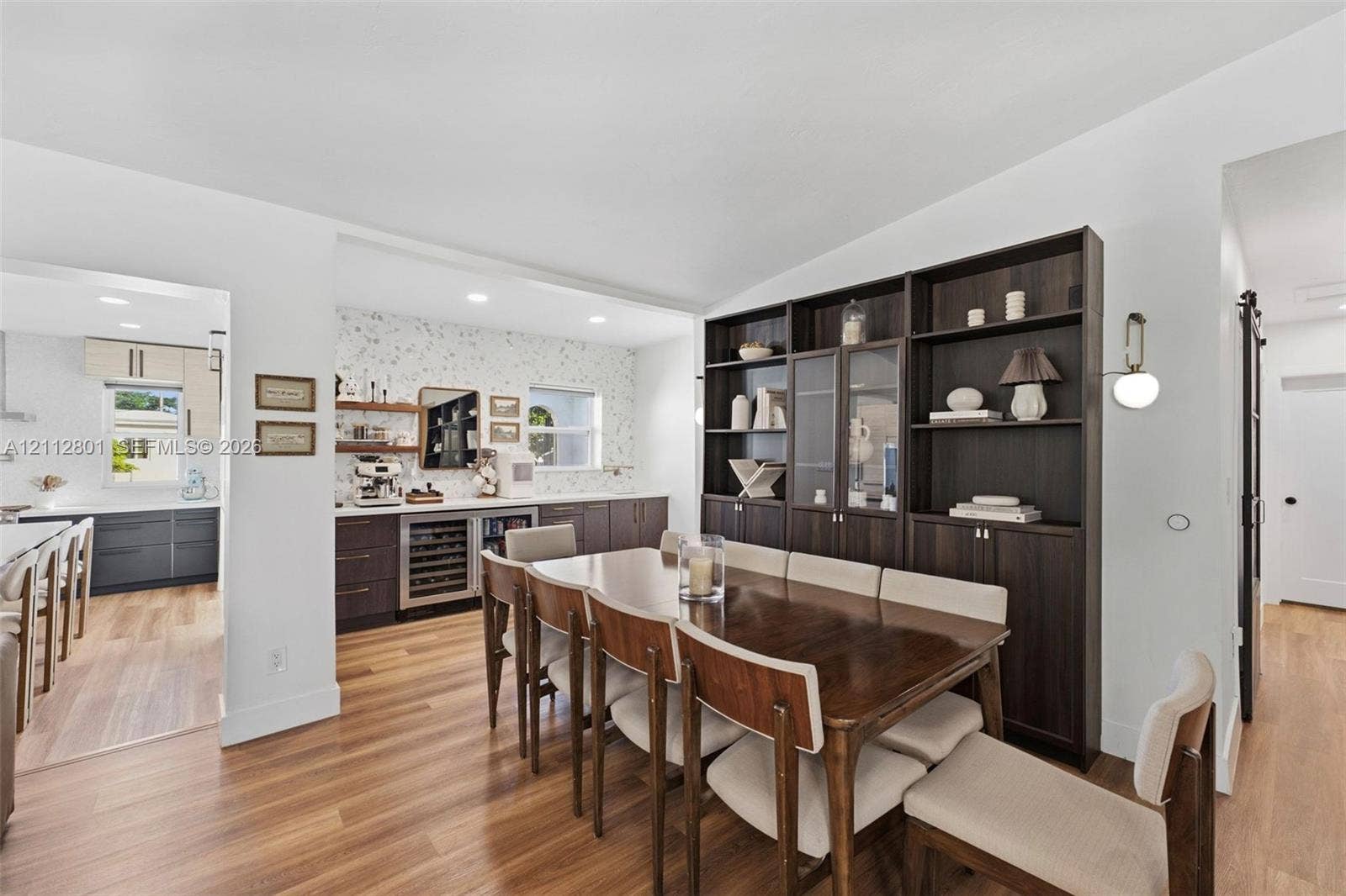 3241 SW 84th Court, Miami, FL 33155 Wood-finish flooring, floor-to-ceiling dark wood built-in cabinetry, custom wet bar with under-counter refrigeration, recessed lighting, and modern wall-mounted light fixture