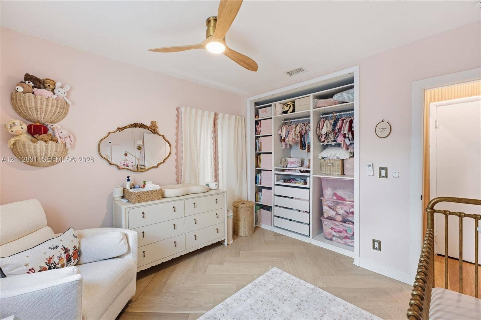 3241 SW 84th Court, Miami, FL 33155 Custom built-in storage unit with open shelving and drawers, light-toned wood-finish flooring in a herringbone pattern, and a ceiling-mounted wooden-blade fan with integrated lighting
