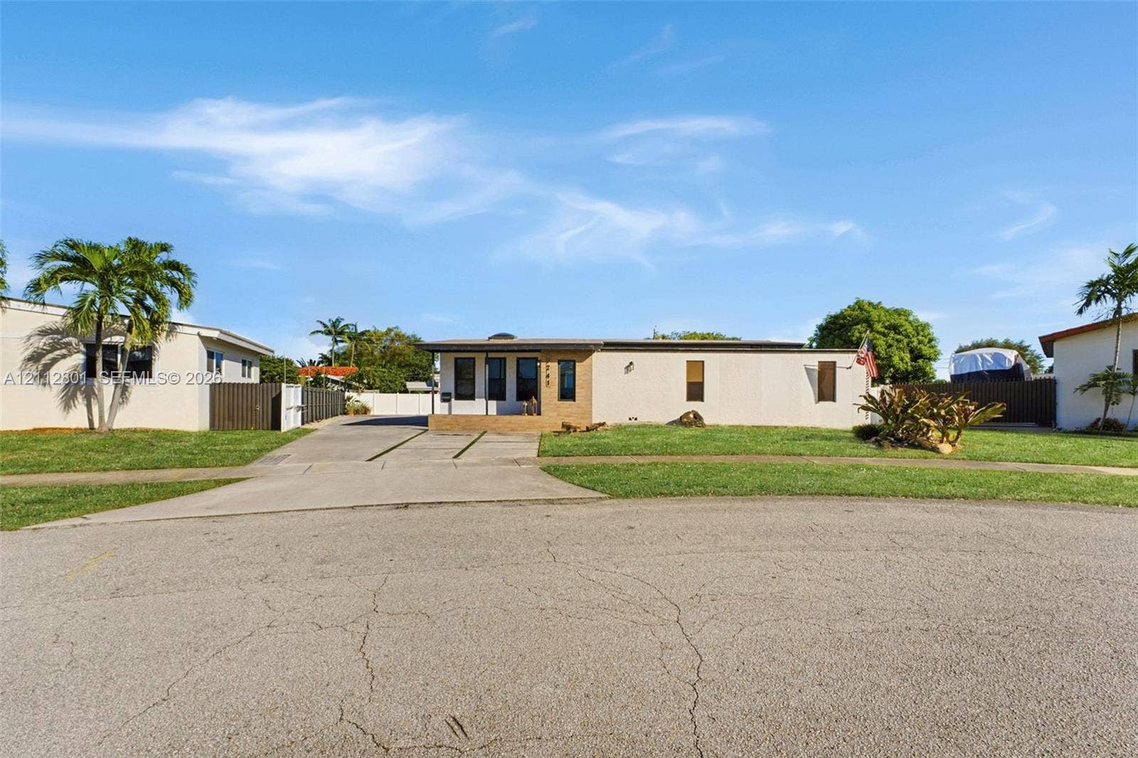 3241 SW 84th Court, Miami, FL 33155 Single-story exterior featuring a light-toned stucco facade, concrete driveway, masonry retaining wall, and landscaping