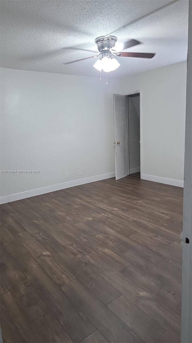 Neutral-toned interior room featuring wood-finish flooring and a central ceiling fan with integrated lighting