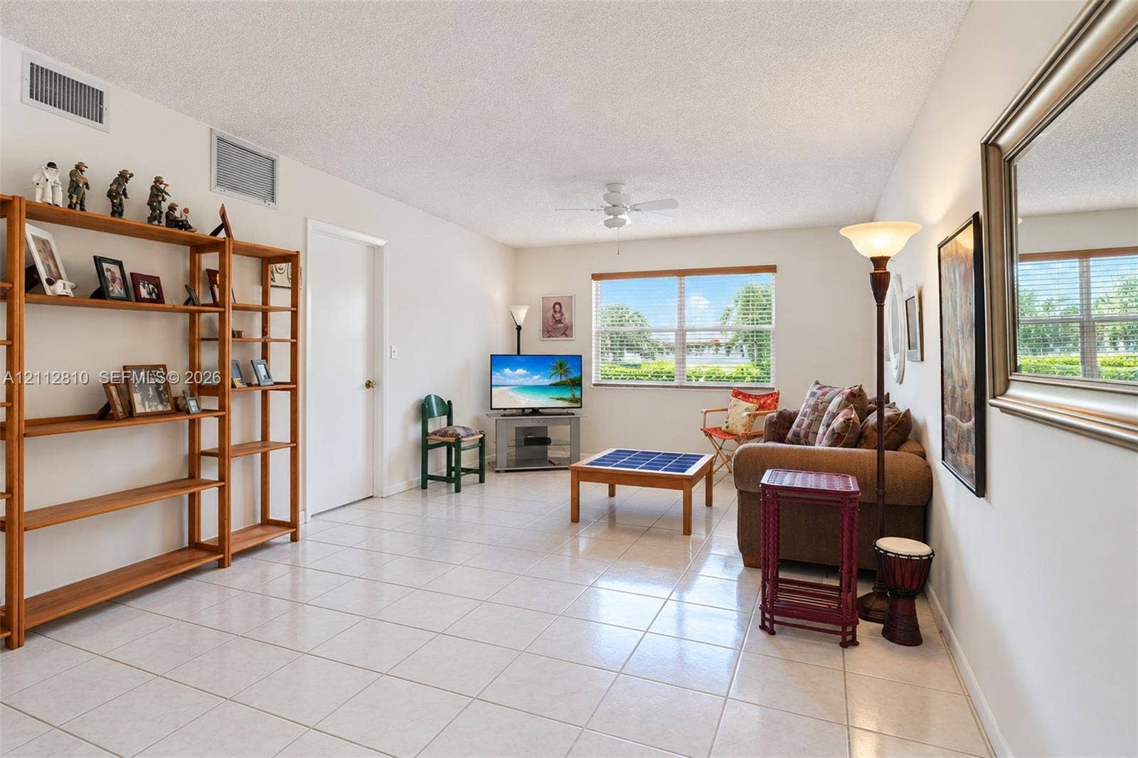 1920 NE 1st Terrace, #107H, Wilton Manors, FL 33305 Living area featuring neutral tile flooring, a ceiling fan with integrated lighting, and a window with exterior scenery