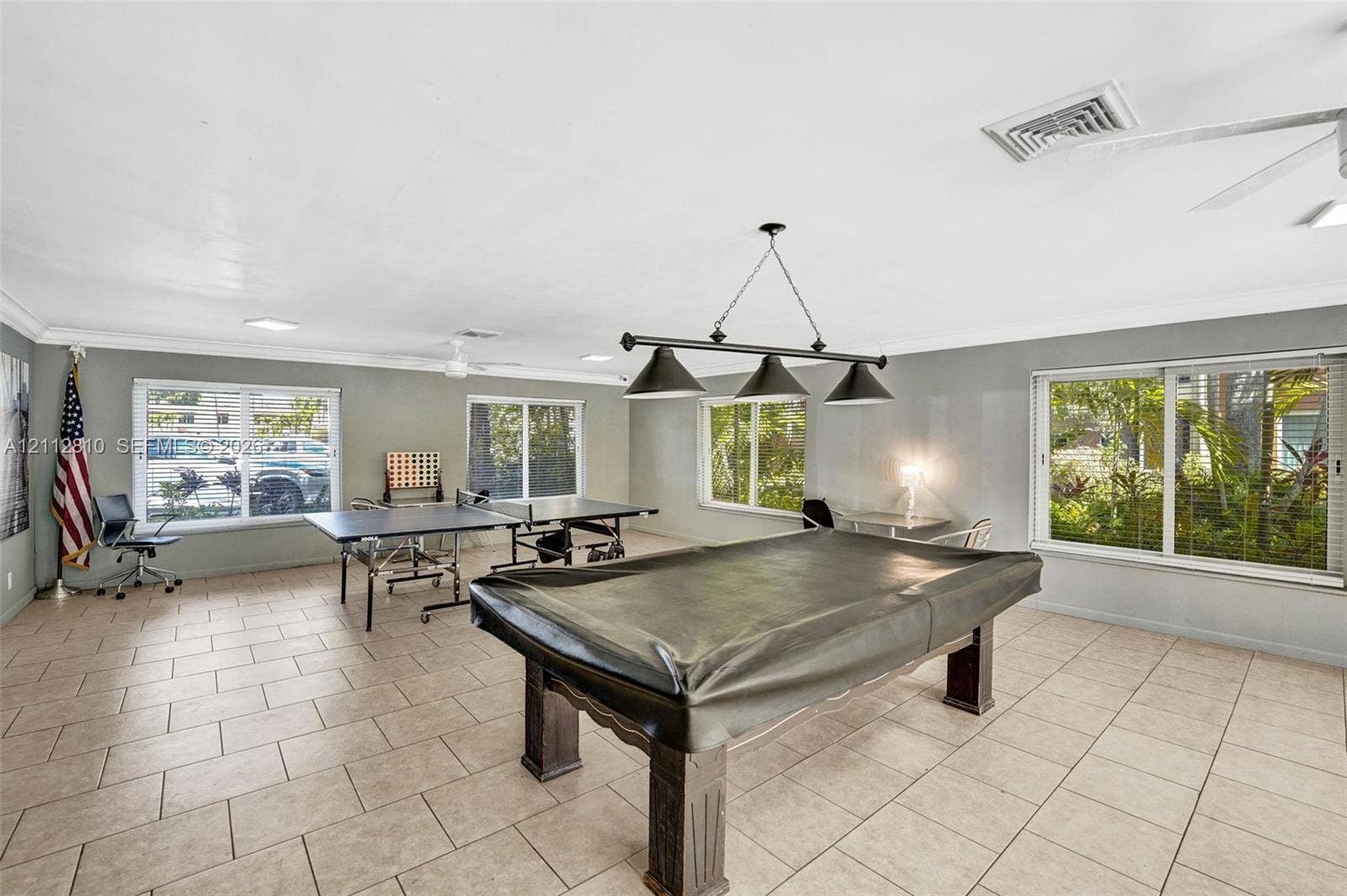 1920 NE 1st Terrace, #107H, Wilton Manors, FL 33305 Spacious room featuring tile flooring, crown molding, a three-light pendant fixture, recessed lighting, and multiple large windows