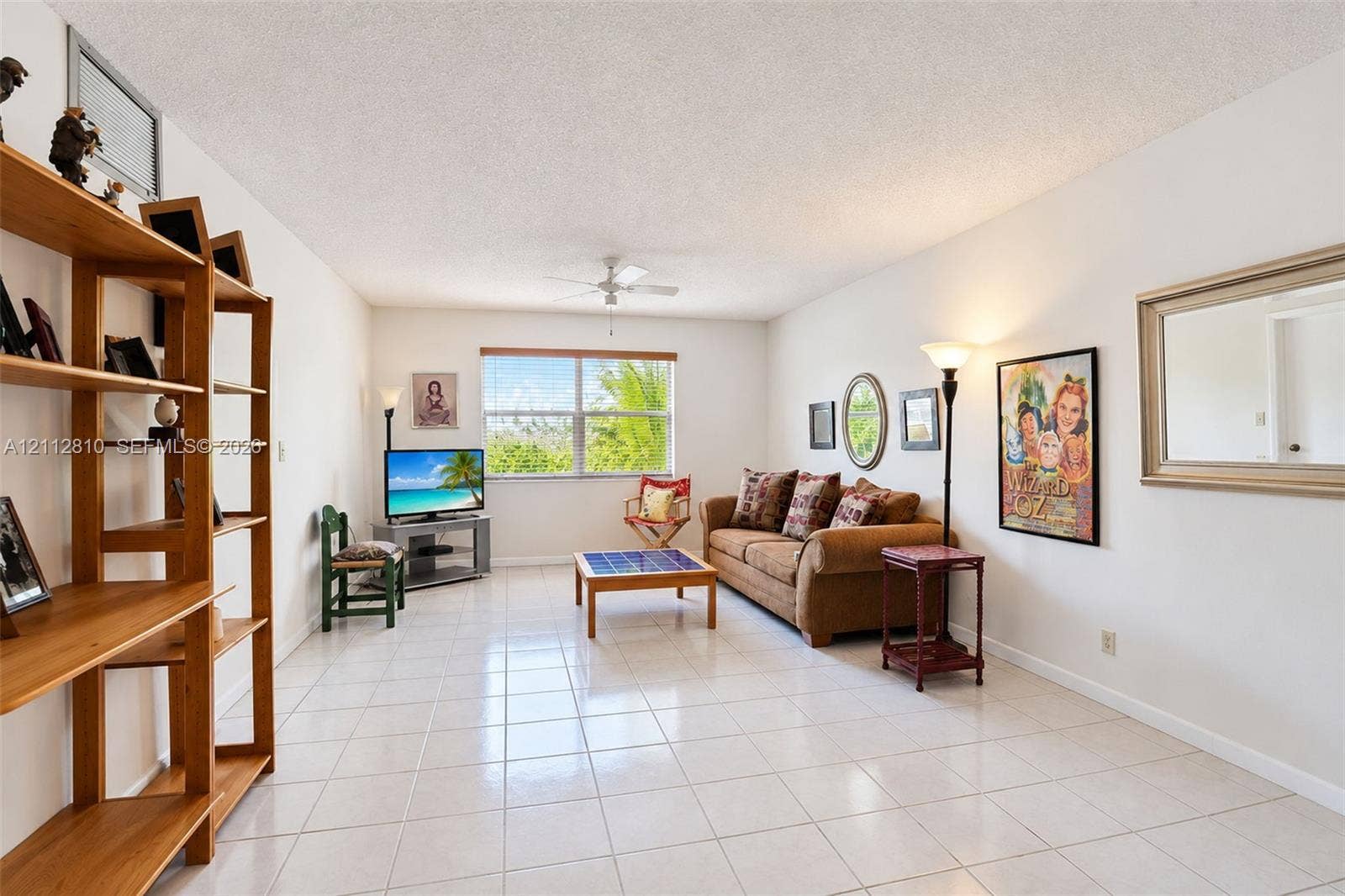 1920 NE 1st Terrace, #107H, Wilton Manors, FL 33305 Living area featuring neutral tile flooring, a large picture window, and a ceiling fan with integrated lighting