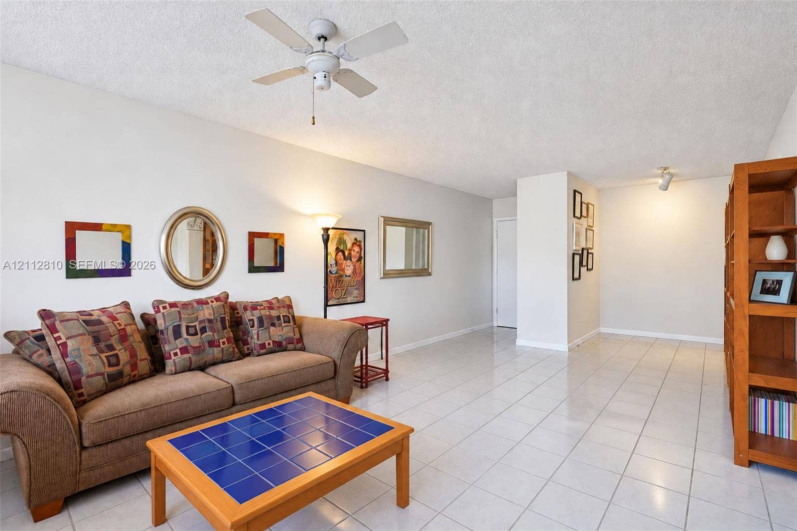 1920 NE 1st Terrace, #107H, Wilton Manors, FL 33305 Living area featuring light-toned ceramic tile flooring, a textured ceiling finish, and a center-mounted ceiling fan with light fixture