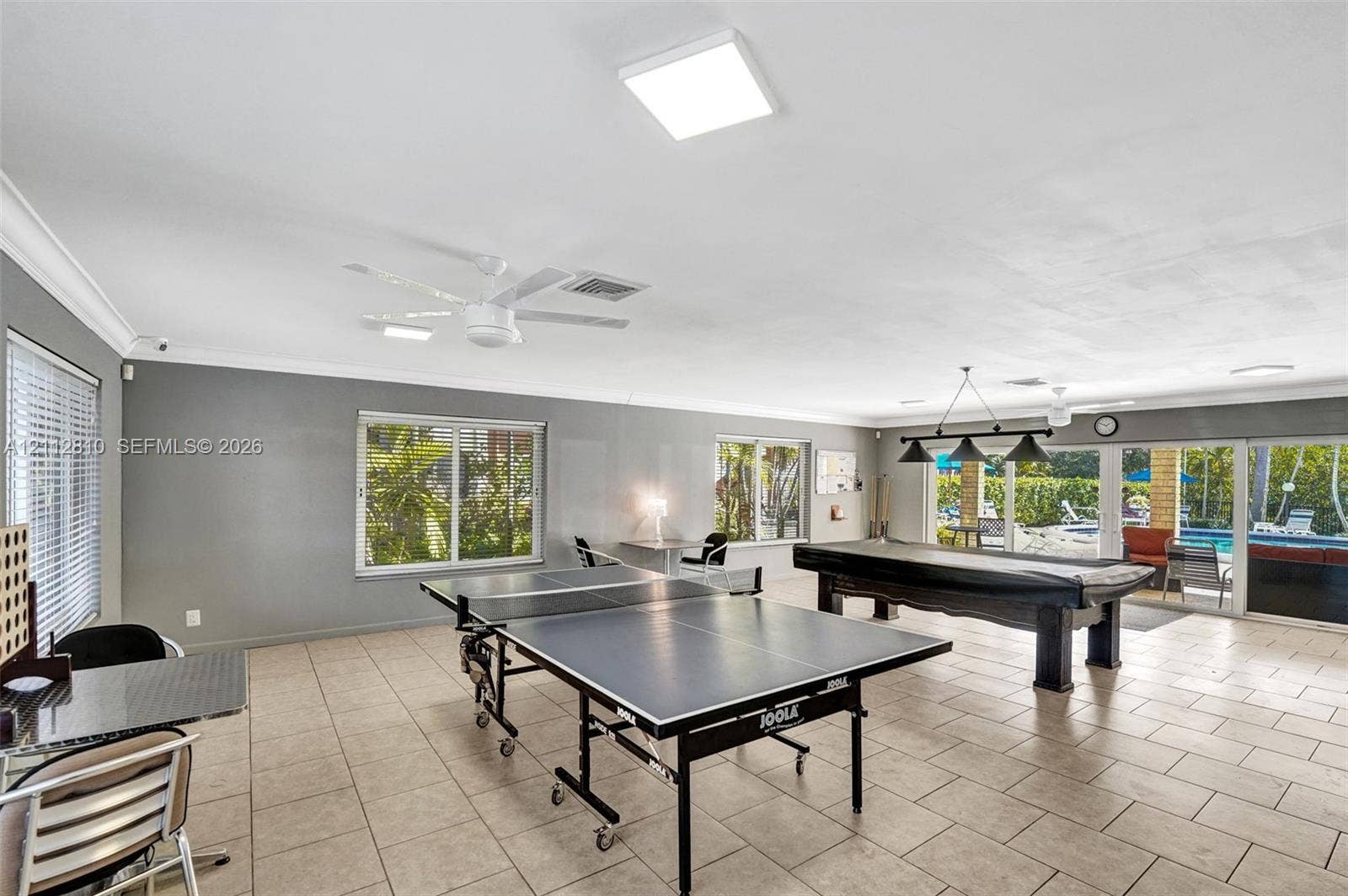 1920 NE 1st Terrace, #107H, Wilton Manors, FL 33305 Spacious interior featuring neutral tile flooring, recessed and pendant lighting, ceiling fans, and large windows and glass sliding doors