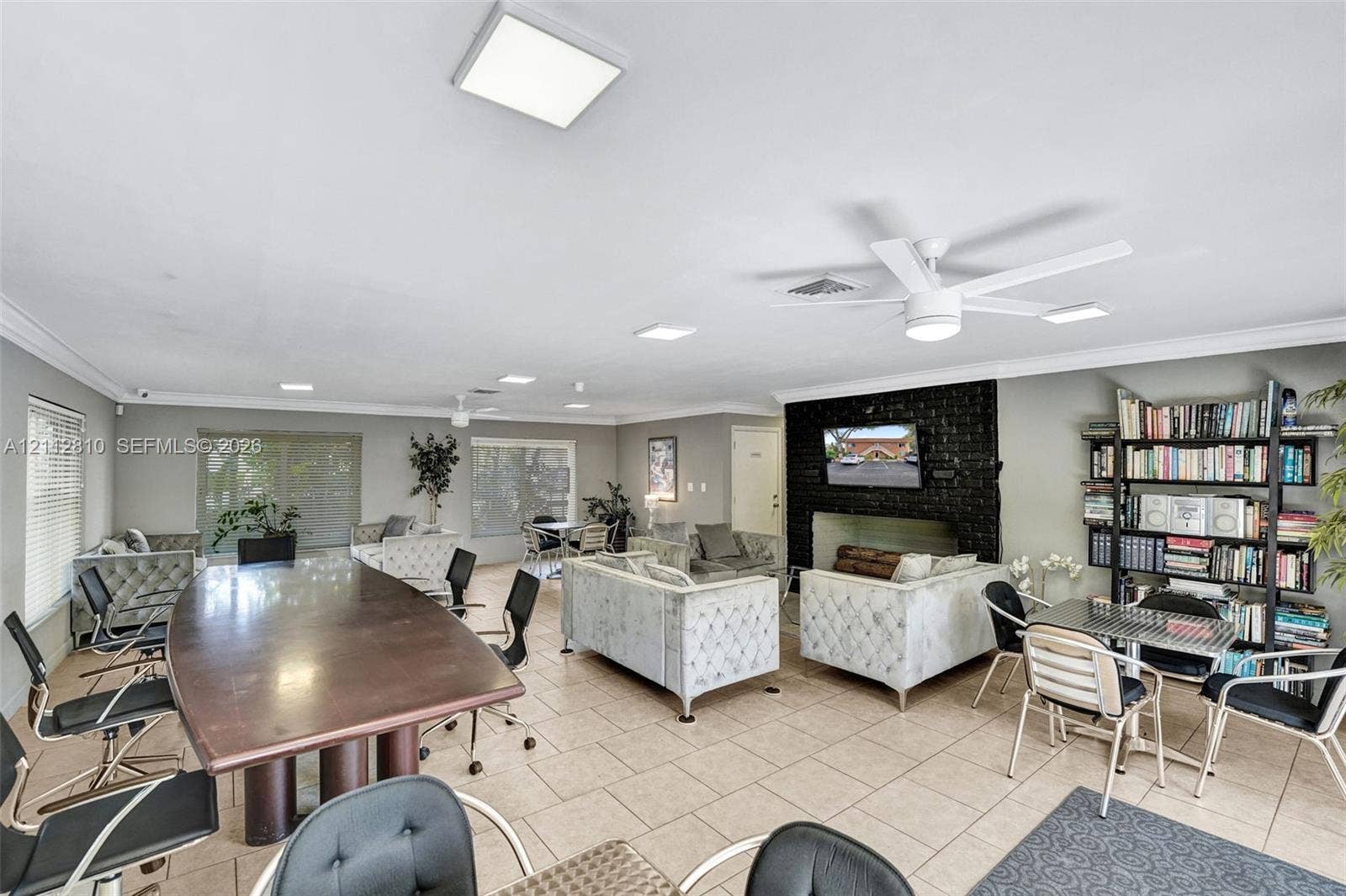 1920 NE 1st Terrace, #107H, Wilton Manors, FL 33305 Open-concept area featuring oversized ceramic tile flooring, a dark masonry fireplace, built-in shelving, recessed lighting, and white ceiling-mounted fans