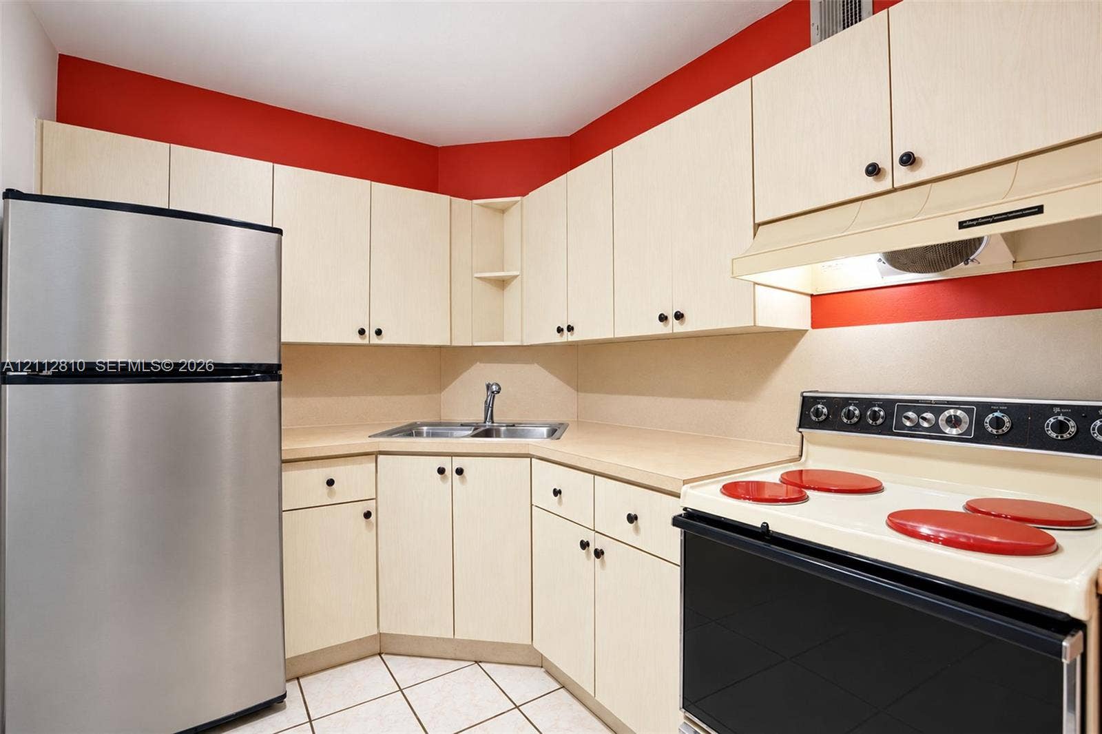 1920 NE 1st Terrace, #107H, Wilton Manors, FL 33305 Kitchen featuring light-finish cabinetry, stainless steel refrigerator, integrated range, dual-basin sink, and tile flooring