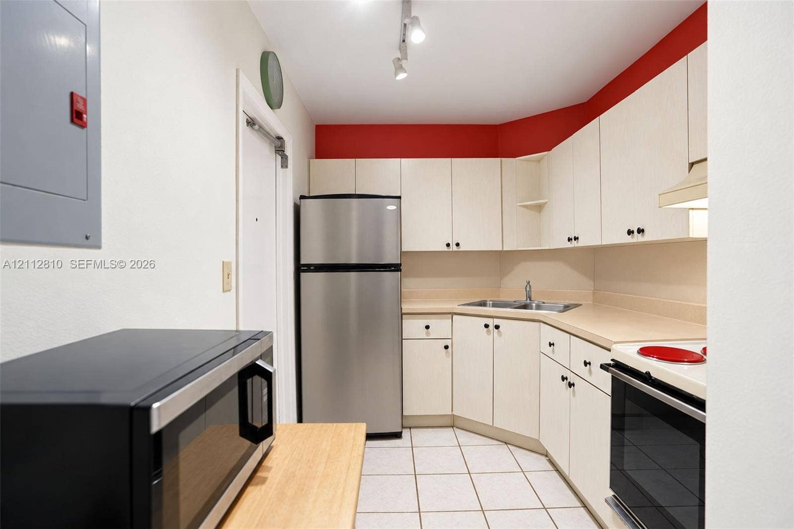 1920 NE 1st Terrace, #107H, Wilton Manors, FL 33305 Kitchen featuring stainless steel refrigerator, white cabinetry with integrated hardware, dual-basin sink, and tile flooring