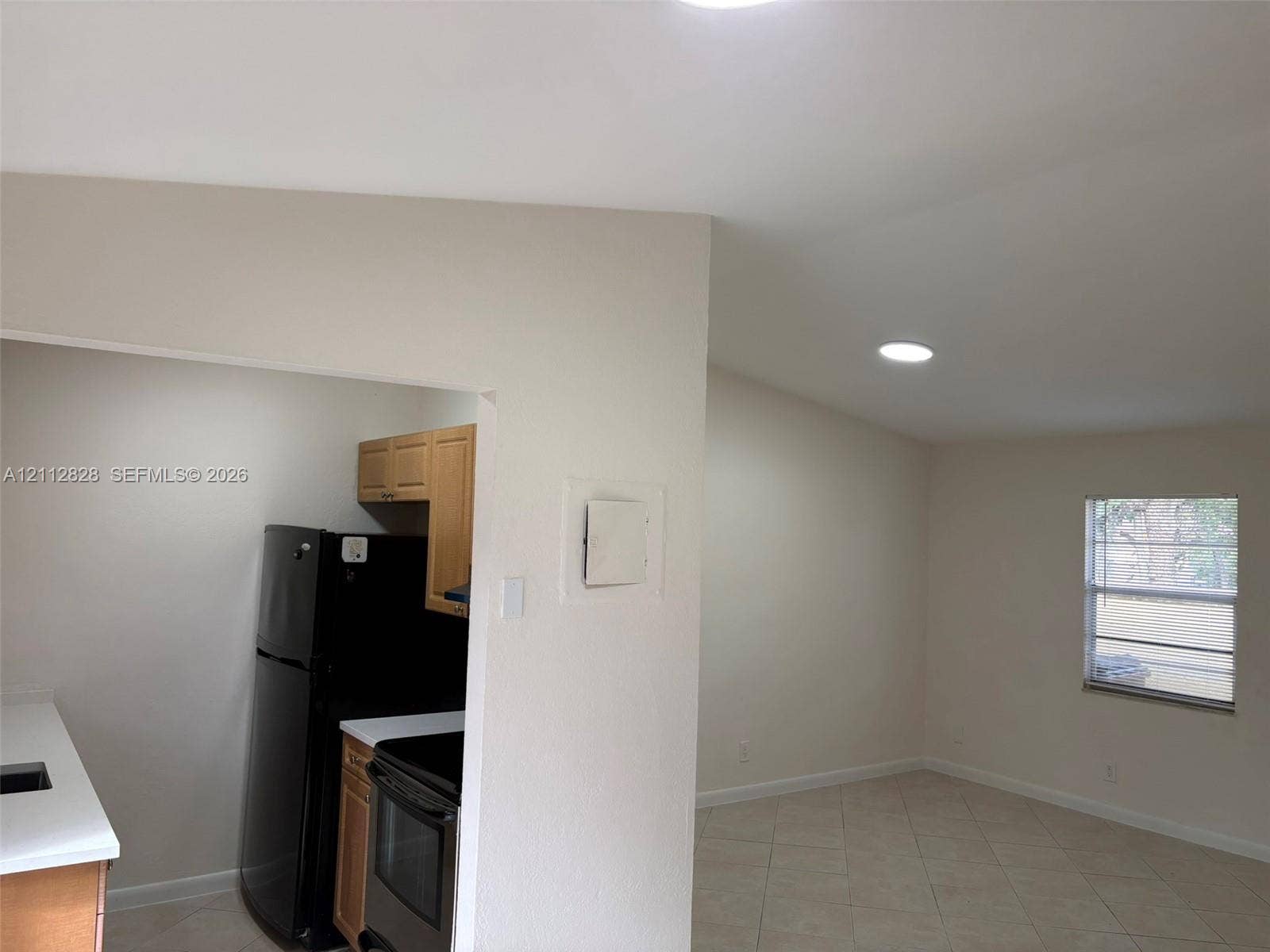 508 NW 43rd Place, Deerfield Beach, FL 33064 Kitchen area featuring light-finish cabinetry, solid-surface countertops, and black appliances, complemented by tile flooring and recessed lighting throughout