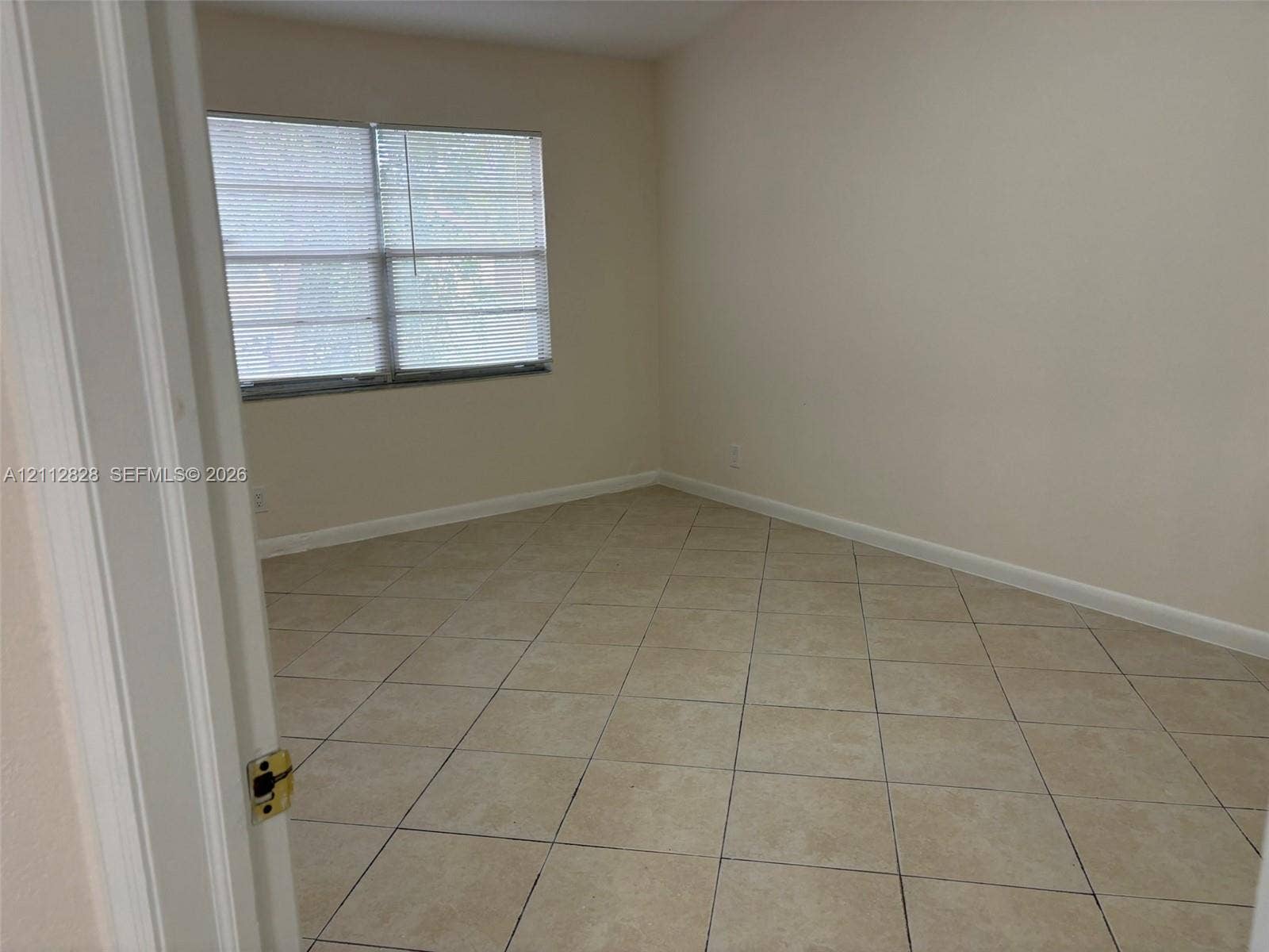 508 NW 43rd Place, Deerfield Beach, FL 33064 Neutral-toned room featuring diagonal tile flooring and large windows with horizontal blinds