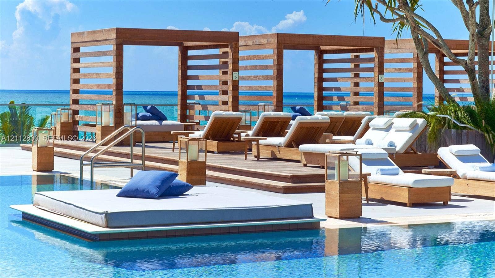 Swimming pool with a raised wood-finish deck, tiered wooden cabanas, and integrated metal railing