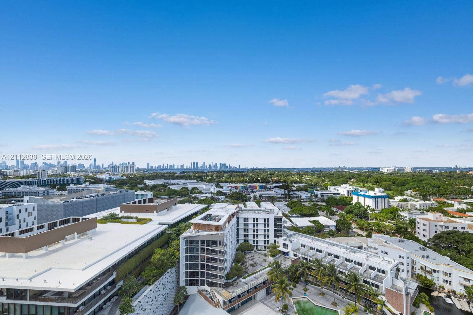 Aerial perspective of the urban landscape featuring mid-rise structures, sprawling greenery, and an expansive cityscape horizon