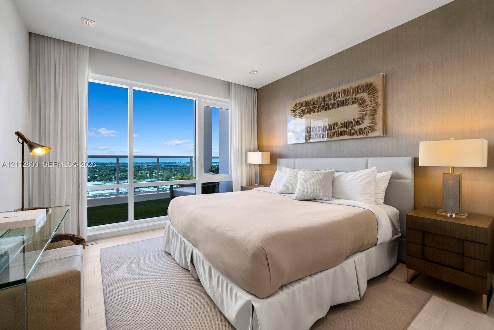 Floor-to-ceiling windows, private balcony access, neutral textured wall covering, and recessed lighting