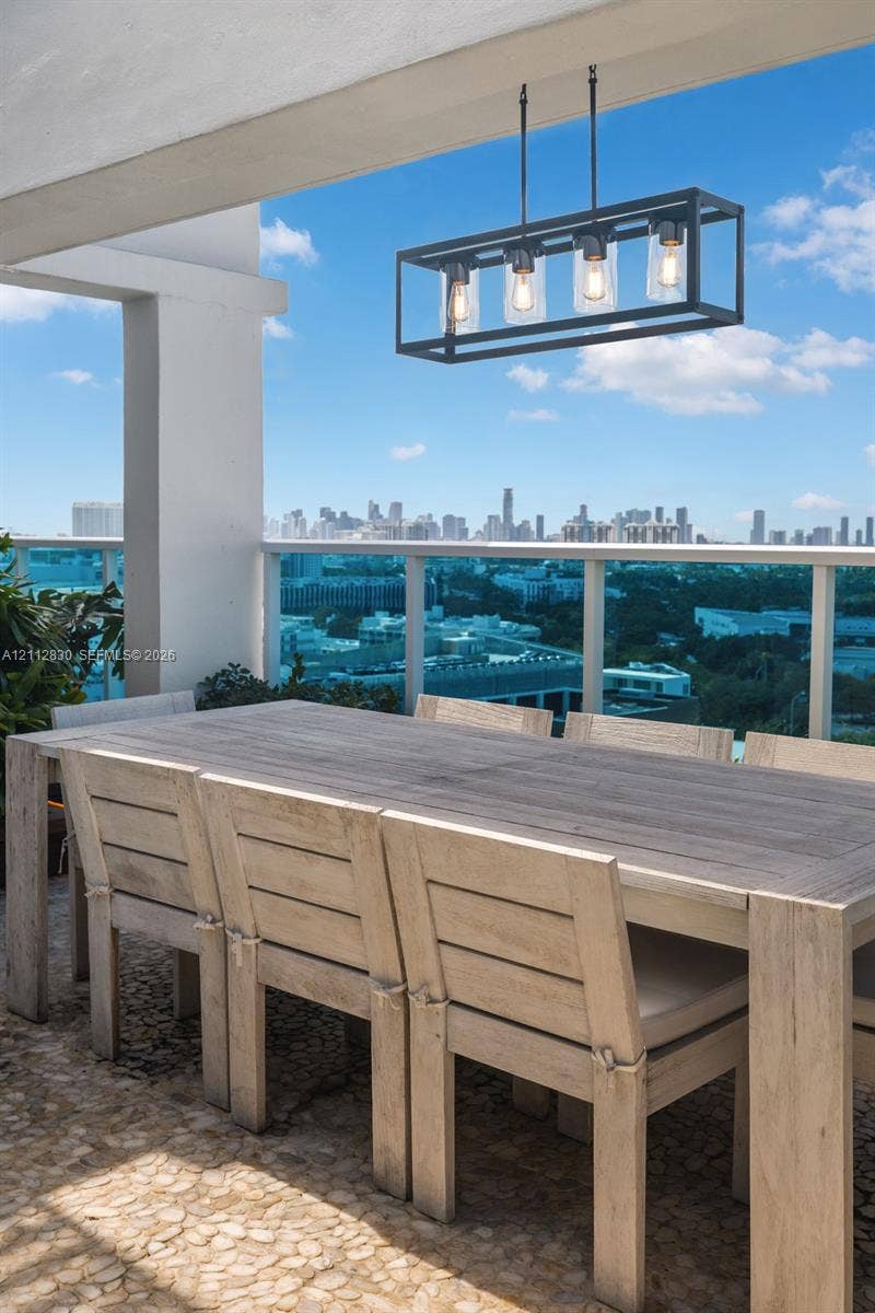 Covered balcony featuring natural stone flooring, a matte black rectangular four-light pendant fixture, and a metal railing